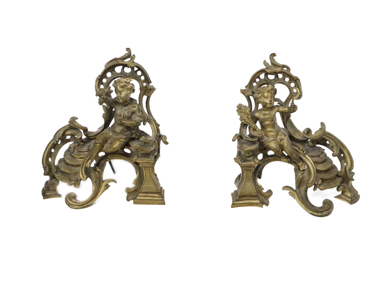 Pair Louis Bronze Figural Chenets: Pair of figural chenets, France, 19th century, the figures being cherubs holding sheaf of wheat, a sickle, and grapes, atop scrolling rococo mounted standing chenets. [14" H x 12" W x 5" D]. Loose mou
