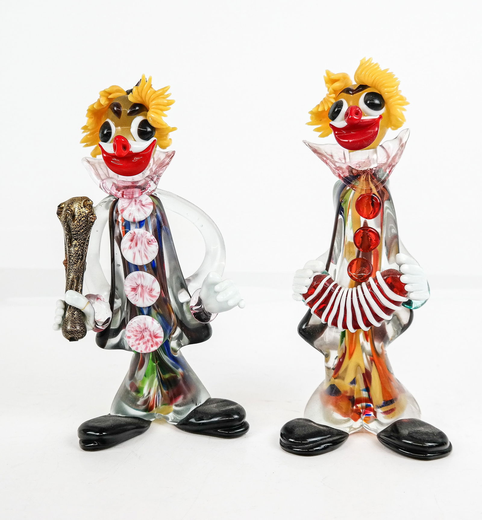 Two Murano Glass Clowns: Two Murano glass clowns, 20th century, including one with an accordion, the other with a bludgeon, unsigned. [Taller: 9" H x 4" W x 3.5" D]. Condition to each is good, repairs to hand of bludgeon