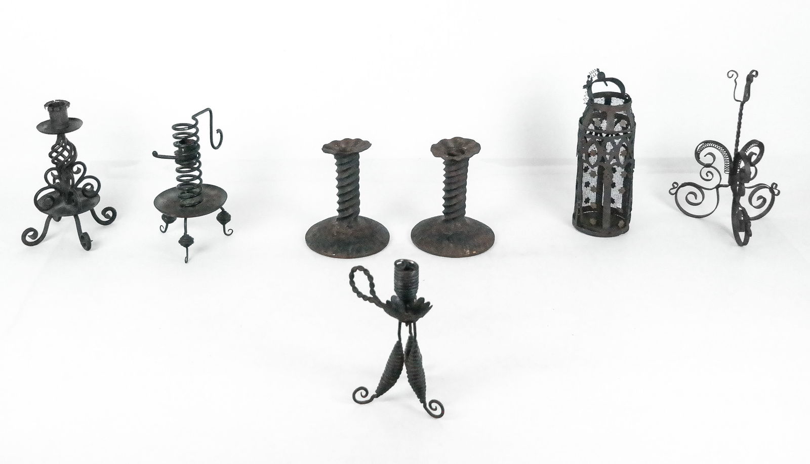 Iron Candlesticks, 7: Collection of candlesticks, early 20th century, comprising a pair of cast iron candlesticks with spiral stems and flared bobeches, a chamber stick on three legs, a chamberstick on three legs with a sp