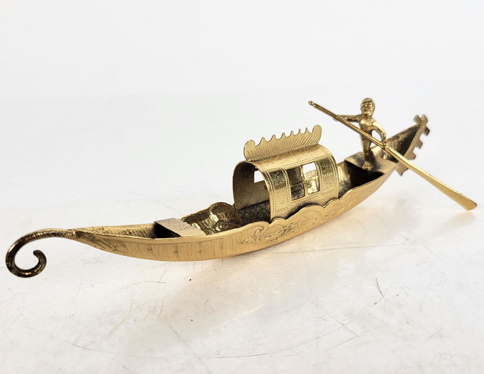 Brass Miniature Venetian Gondola: Miniature brass Venetian gondola with gold-tone finish, circa early 20th century. [1 1/2" H x 1" W x 6" D]. Condition reports and requests for additional photos cannot be accepted on this lot; please