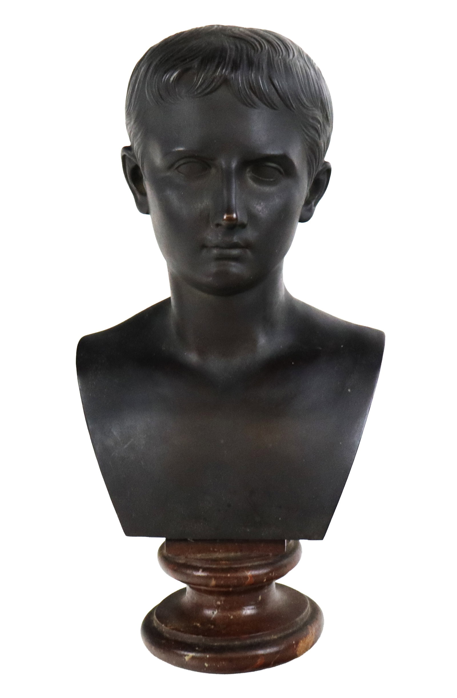 Bronze Bust of August Caesar: Bronze bust of young Augustus Caesar, resting on a wood socle. [15" H x 7.5" W x 6" D]. Overall condition is good, with wear and discoloration to wood base.
