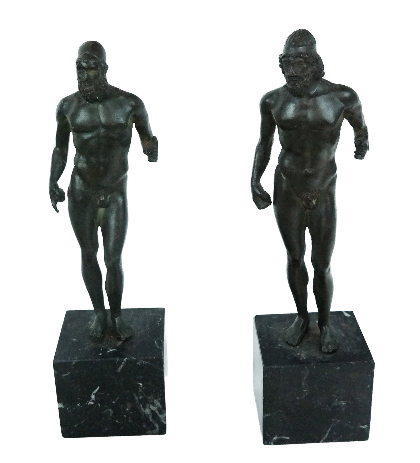 Two Diminutive Sculptures after Bronzi di Riace: Two diminutive sculptures after the ancient Bronzi di Riace on black marble bases, rendered in metal with a faux bronze finish. [Taller: 11" H x 2.75" Square]. Condition is good with some wear to