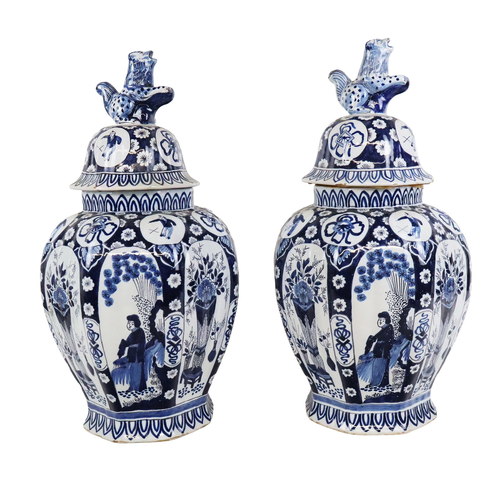 Pair of Delft Covered Urns: Pair of Delft covered urns, Netherlands, 20th century, with lion finials and figural and floral decoration to lower, marked to each at base. [18" H x 9" Diameter]. Condition to each is good with some 
