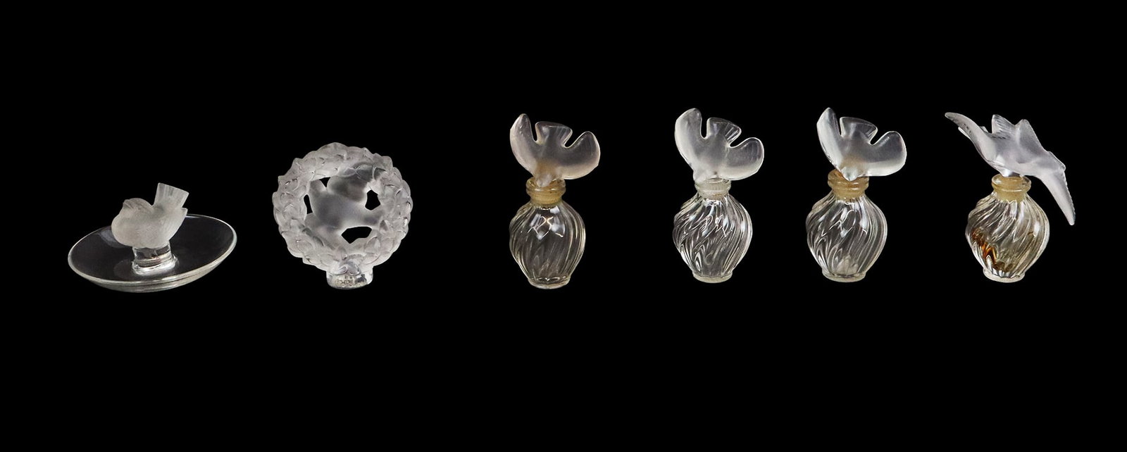 Assorted Lalique Articles, 6: Six articles of Lalique satin finished crystal, 20th century, including a Dove in Wreath figure, a ring dish with bird, and four Nina Ricci for Lalique perfume bottles with satin crystal stoppers, all