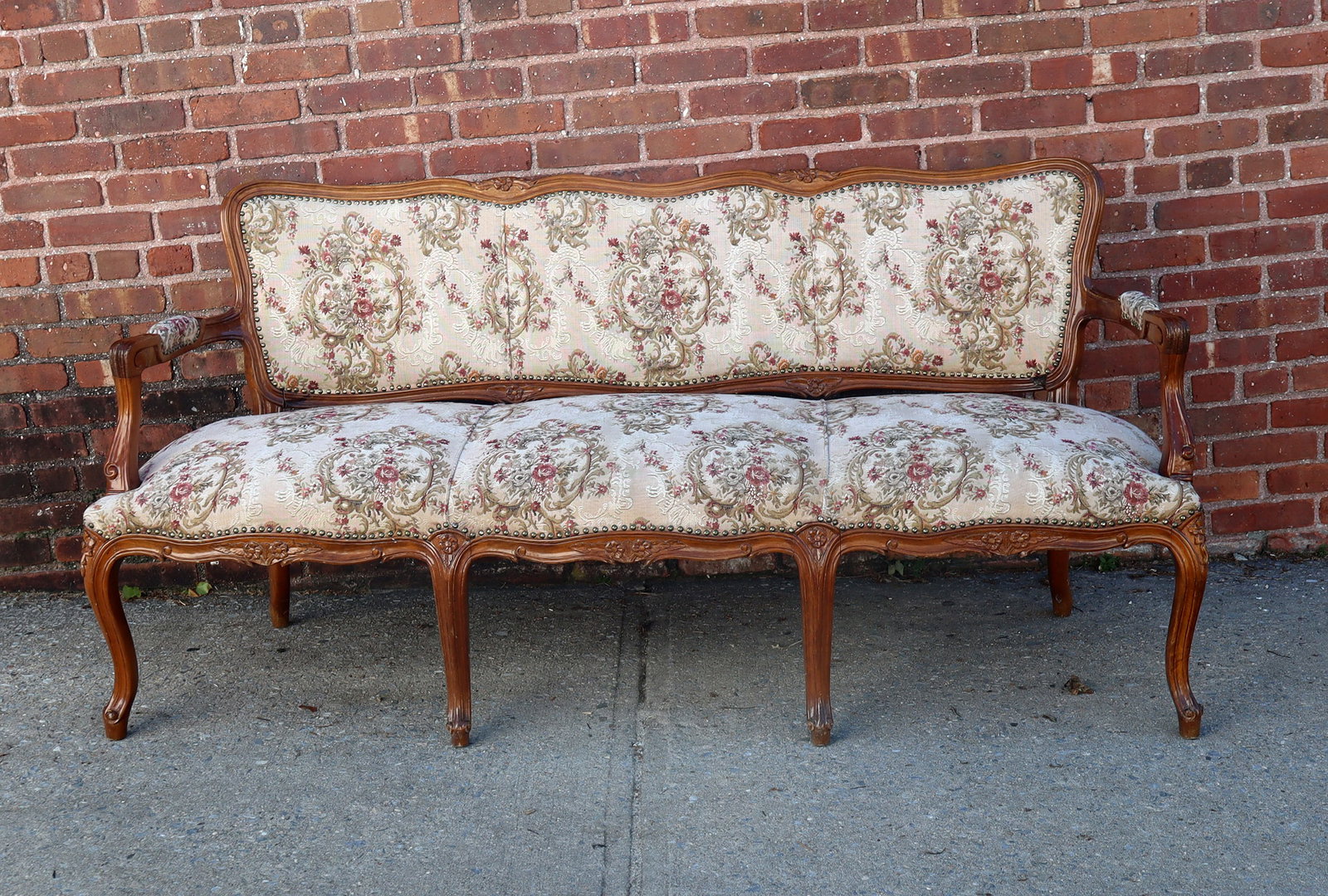 Louis XV Upholstered Settee: Louis XV upholstered settee, 20th century, with three seats, a carved frame, and brass tack detail. [31" H x 69" W x 21" D; seat height: 19"]. Condition is good.