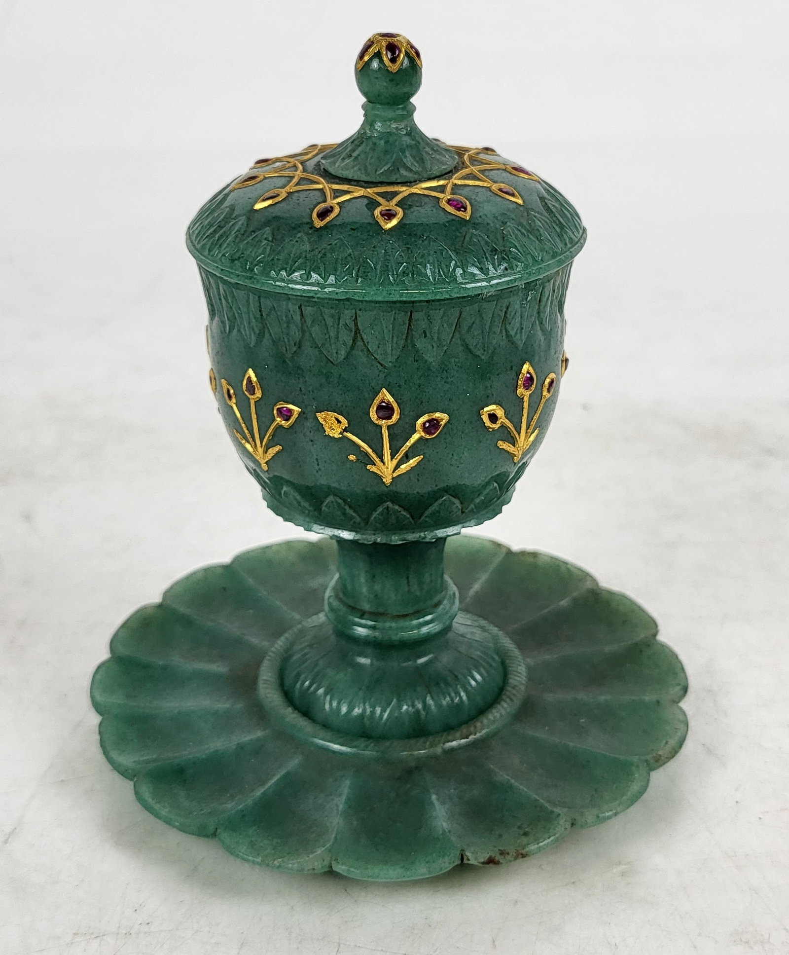 Indian Mughal Style Cup, Cover and Saucer: Indian Aventurine Mughal Style Cup, Cover and Saucer, the cover and cup having gilt painted metal mounts and inset red stones, carved with acanthus leaf trim, the saucer in the form of an open flower 