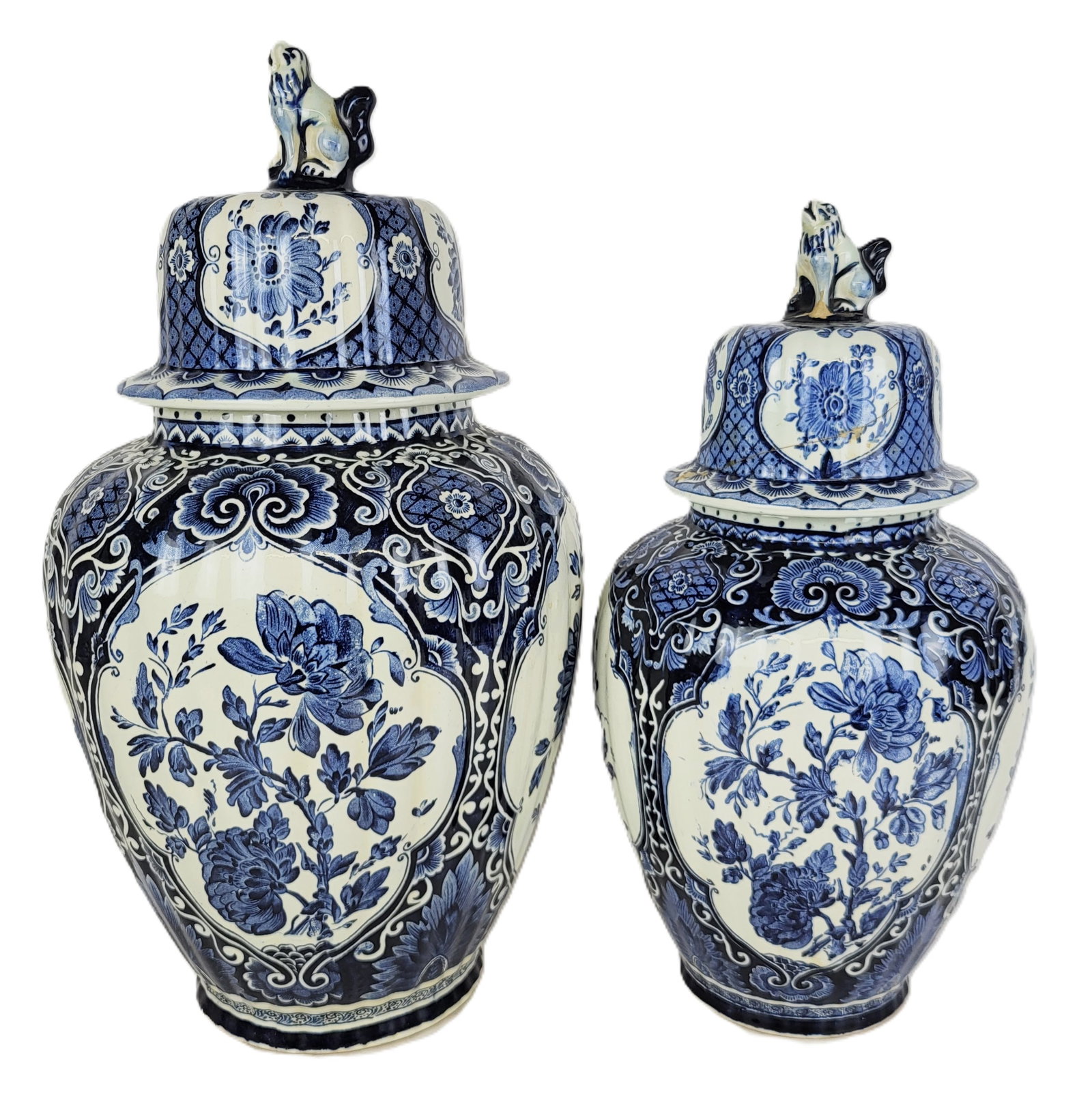 Delft Royal Sphinx by Boch, Two Covered Urns: Two Delft covered urns, 20th century, produced by Royal Sphinx by Boch, each with transfer decoration and dog form finials, marked to base of each. [Taller: 19" H x 10.5" Diameter]. Condition to large
