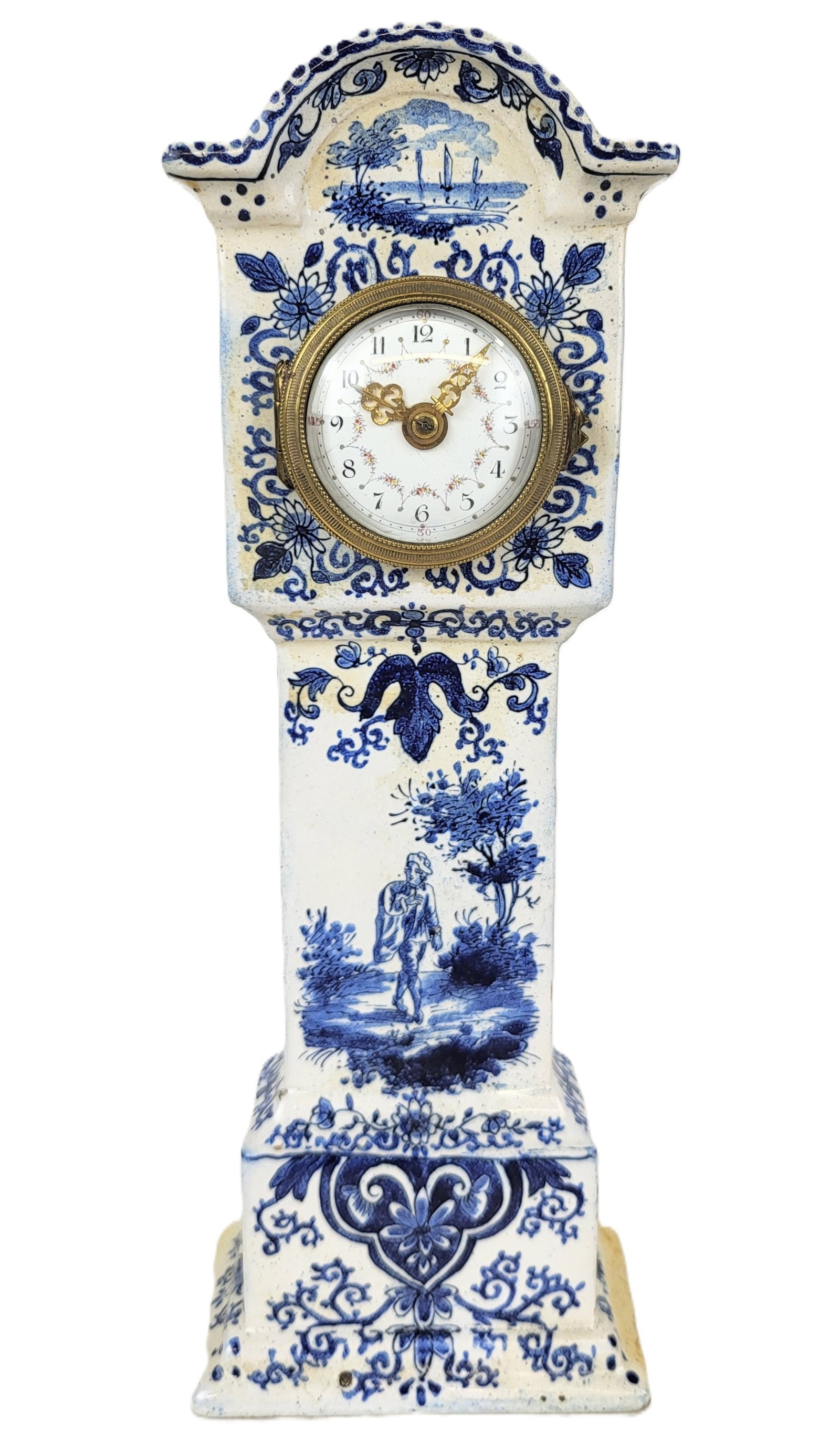 Delft Porcelain Clock: Delft porcelain clock, 20th century, with a faience decorated case and enamel face, marked to works at reverse; case unmarked. [11" H x 4" W x 1.75" D]. Condition is good; works untested.