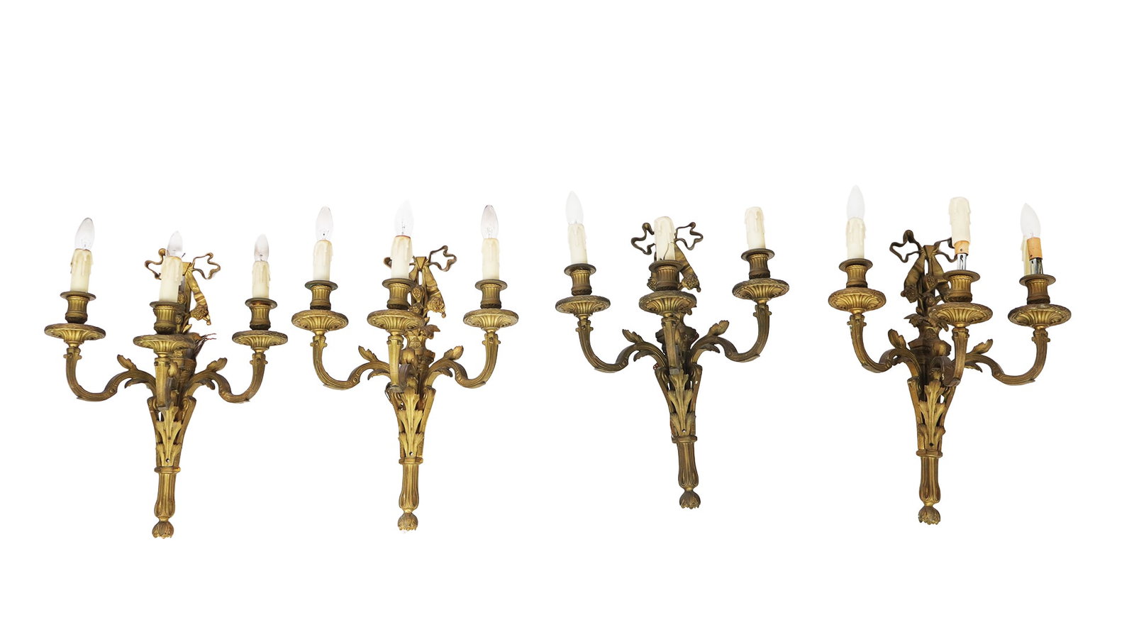 Four Louis XV Gilt Sconces: Four Louis XV gilt metal sconces, 20th century, with fruit and ribbon detail to upper and three lights. [20" H x 15" W x 10" D]. Condition is good with some wear and losses to candle covers; wiring