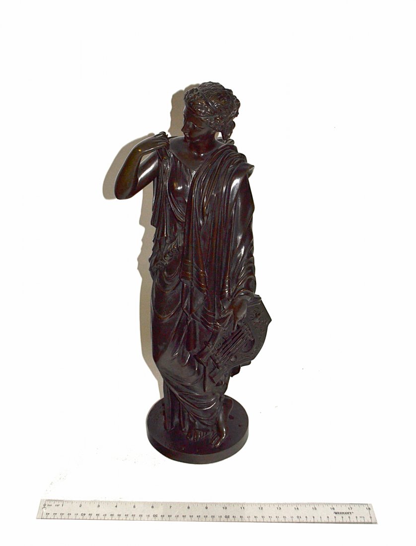 Neoclassical Bronze - The Muse Erato: Standing full-length depiction of the muse with lyre and scroll on a circular base. [6 3/8" D x 22 1/2" H]. Base bears six drilled holes from previous mounts. Surface has dark brown patina.