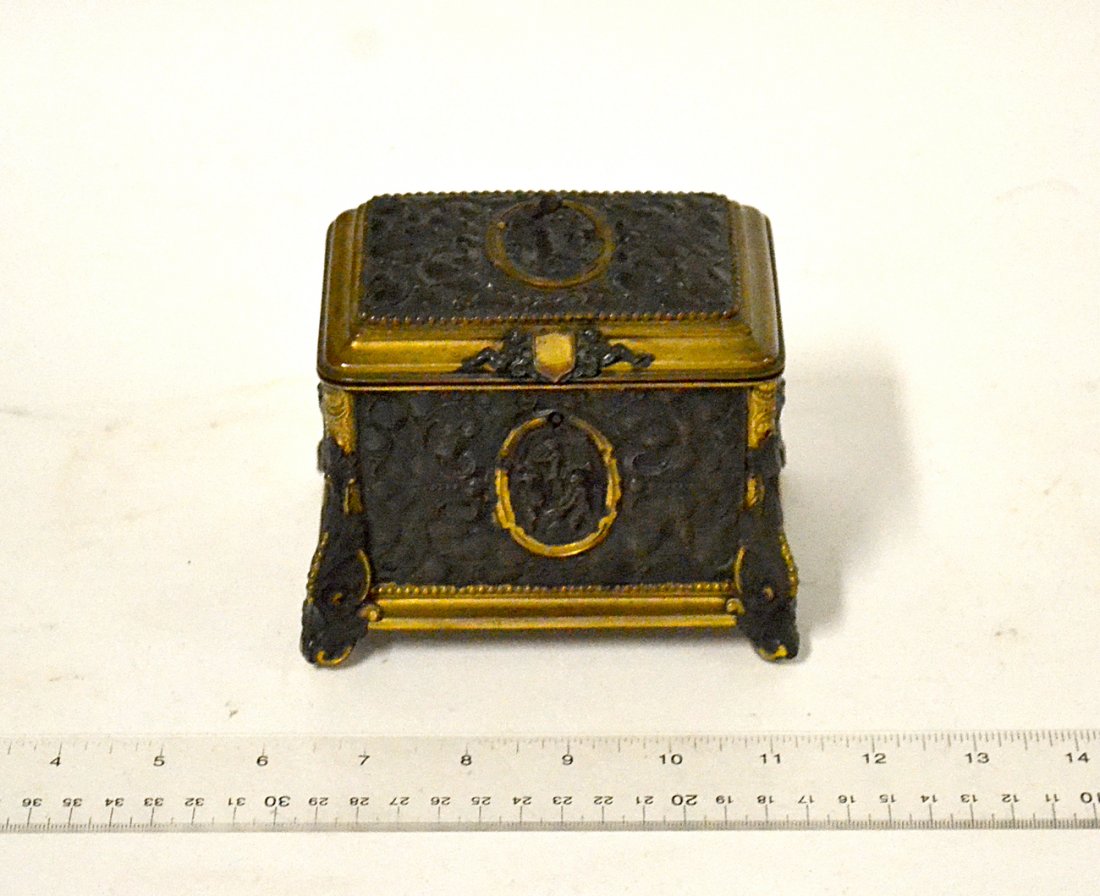 A.B. Paris Repoussé Box: Bronze repoussé decorated casket, figures, cherubs and North Wind motif. [4" x 5" x 3 3/4"]. No repairs or restorations. The lid closes correctly. Interior silk lining is worn and bears irregular sta