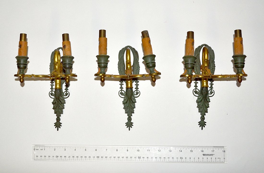 Pair of Empire Two-Light Sconces: A fine pair of (possibly Caldwell) early 20th century sconces having two lights extending out from a dolphin's mouth with wing backs having green patina and dore arms. [8 1/4" x 5 1/4"]