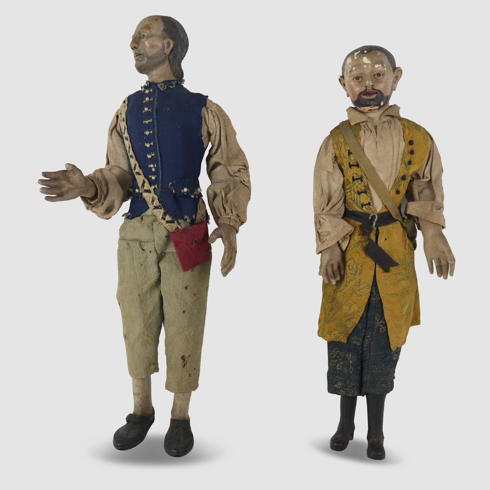 Two Neapolitan Presepe Figures: Two Neapolitan presepe figures, 19th century, with carved and painted heads and hands, and each with a bag, possibly to represent offering. [Taller: 19" H x 5.5" W x 3" D]. Condition is good to fair