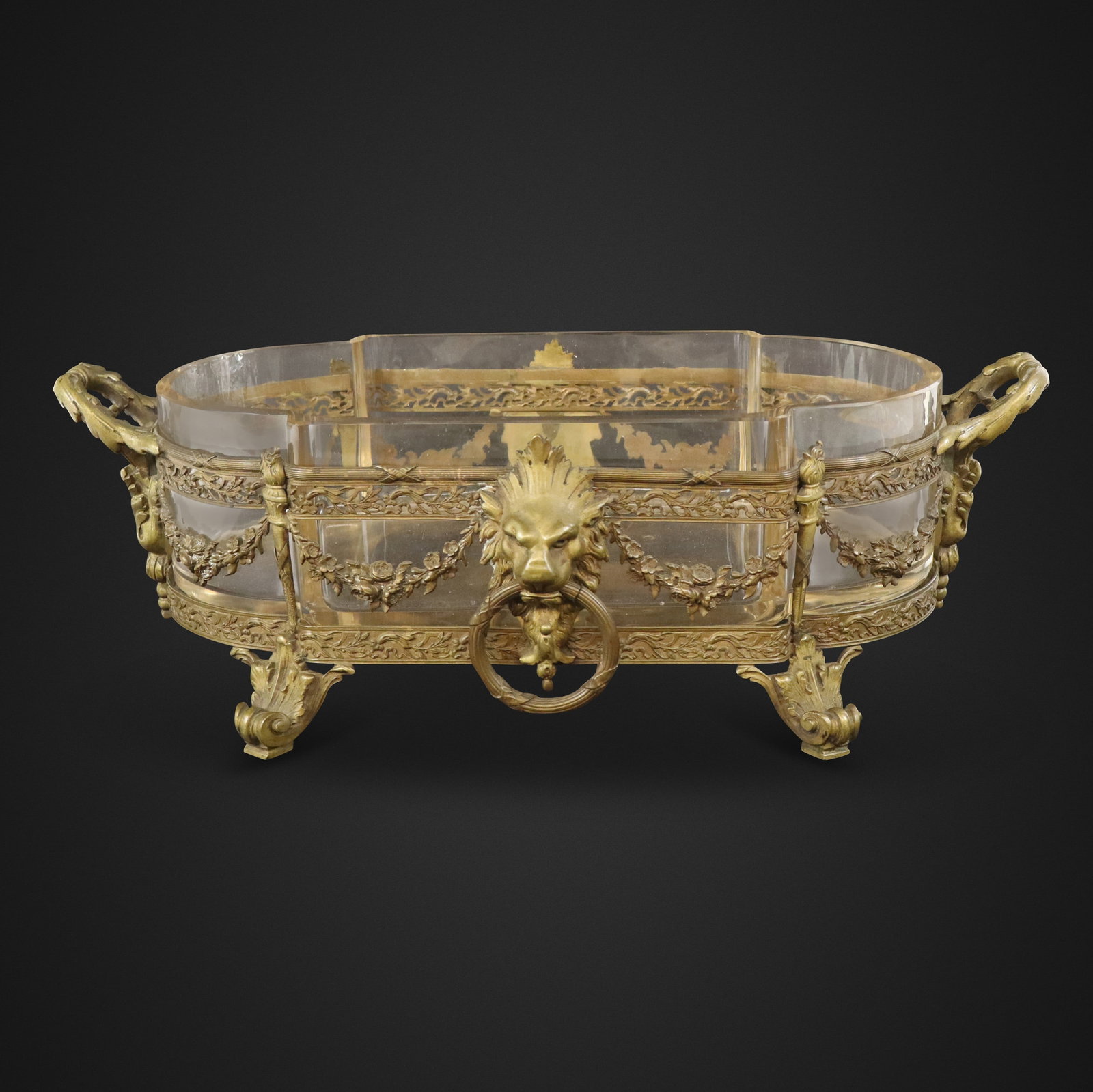Louis XV Bronze and Glass Jardiniere: Louis XV bronze and glass jardiniere or center bowl, 19th century, with lion and swag decoration. [6" H x 18" W x 9" D]. Condition is good with patina to frame and a chip to glass at one side.