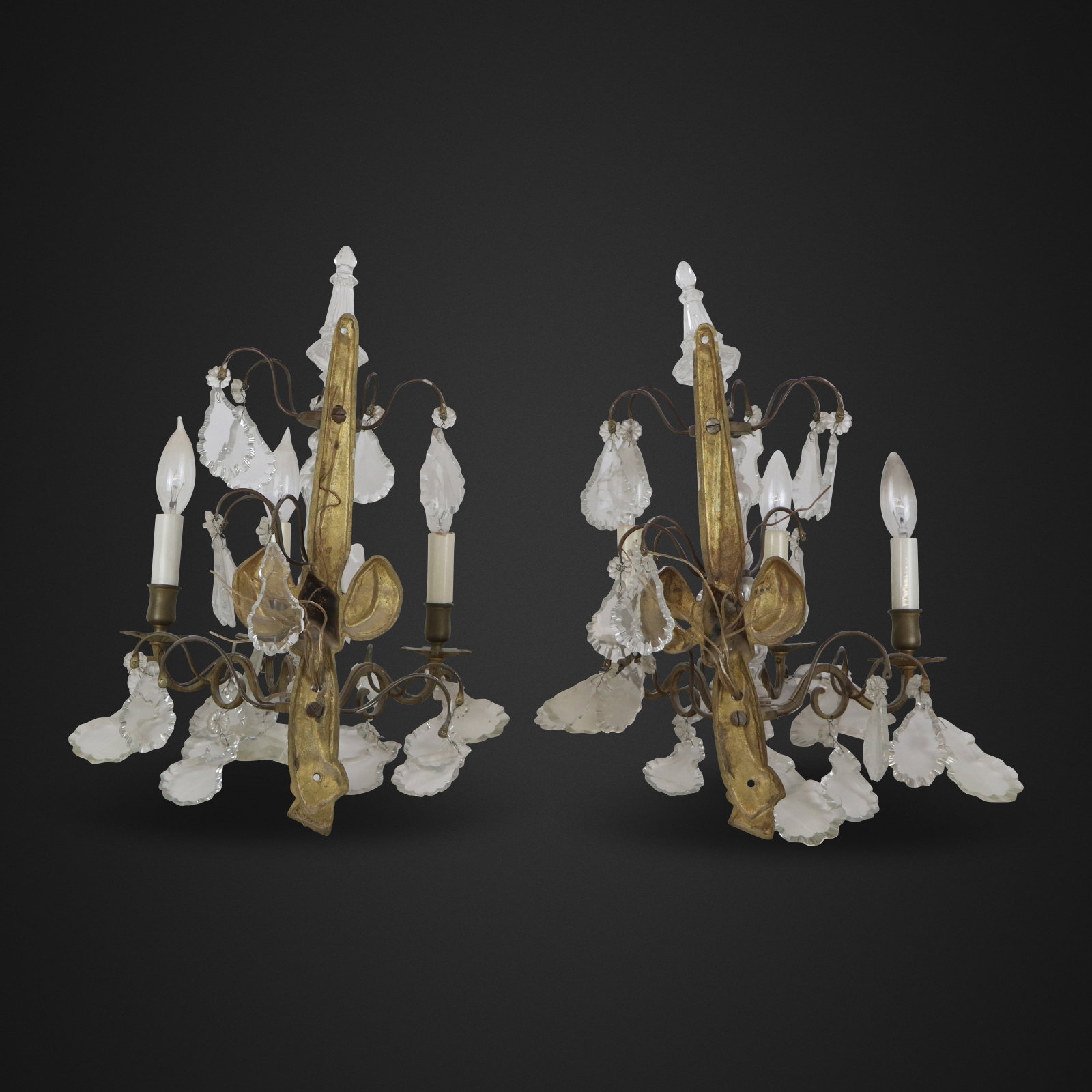 Pair of Louis XV Bronze and Rock Crystal Sconces: Pair of Louis XV bronze sconces, 20th century, with three lights, and crystal, rock crystal, and glass details. [20" H x 12" W x 9" D]. Condition is good with some elements loose where affixed, minor 