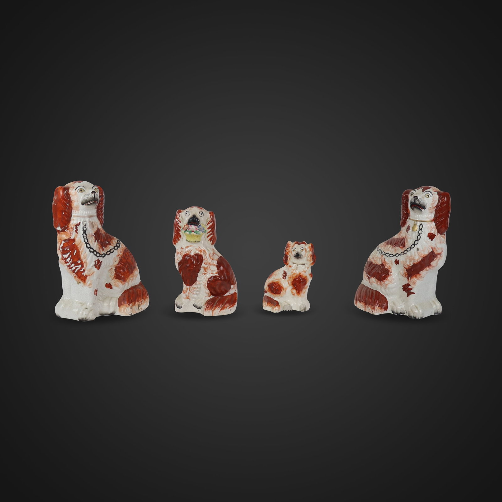 A Pair and Two Other Staffordshire Porcelain Dogs: Four Staffordshire porcelain dogs, England, 19th century, comprising a pair of dogs, a smaller dog with a basket of flowers, and a small dog with bow, all hand-painted, unmarked. [Largest pair: 10.5" 