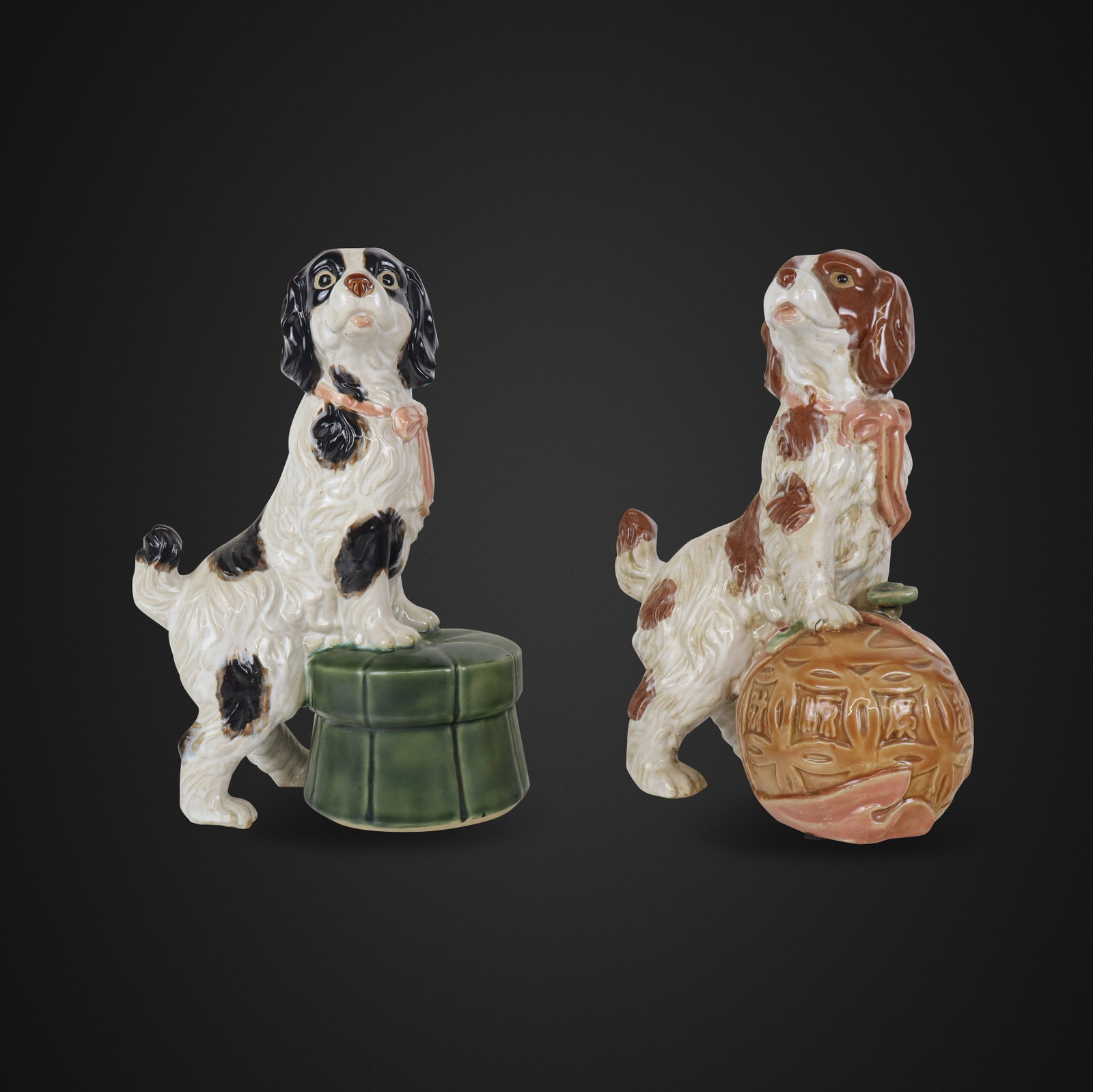 Pair of Porcelain Dogs: Pair of porcelain dogs, 20th/21st century, including ne supported by a ball inscribed in Chinese and the other crouched on a footstool, unmarked. [12.5" H x 8" W x 6" D]. Condition is good.