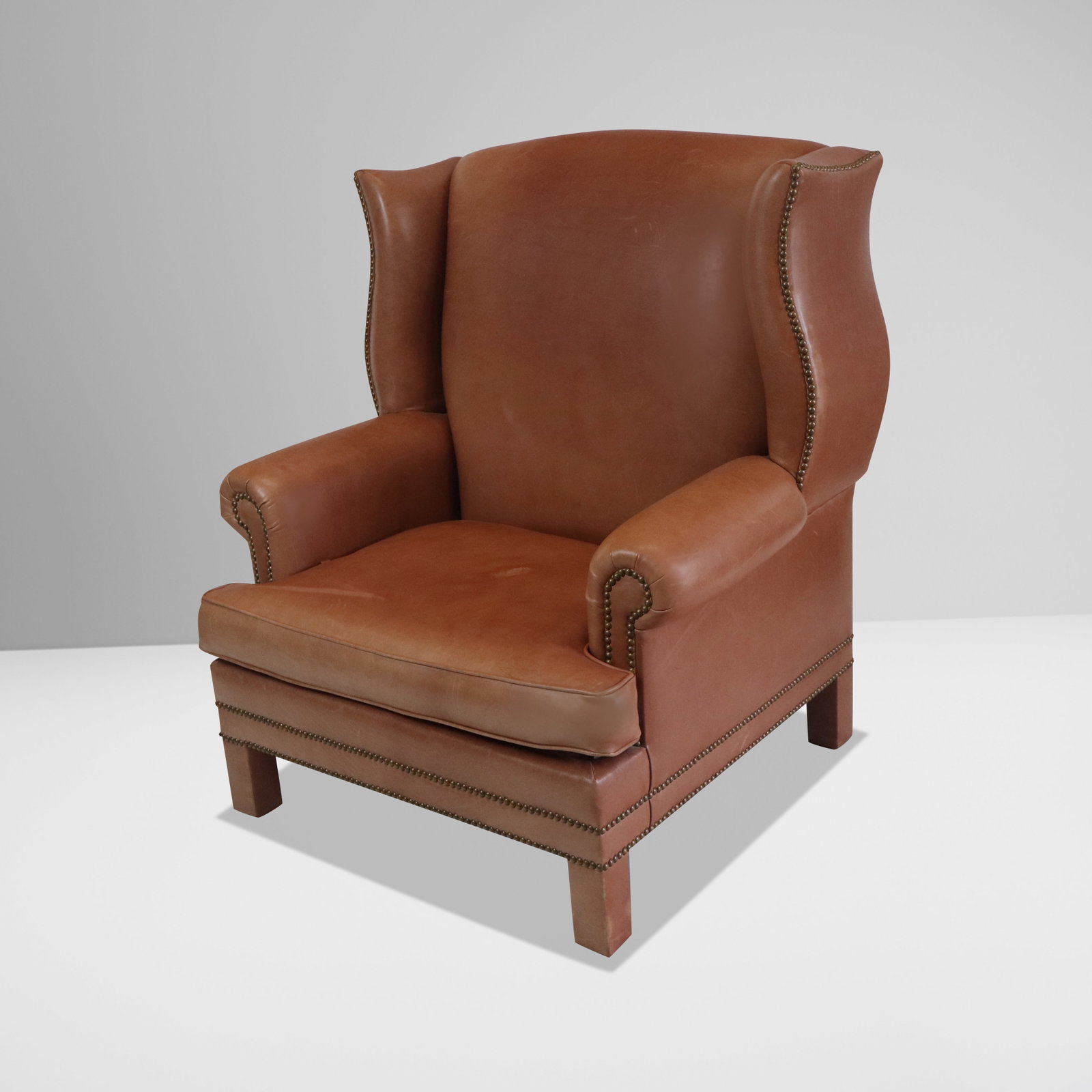 Leather Wingback Armchair: Leather wingback armchair, 20th century, with brass tack detail. [46" H x 40" W x 35" D; seat height: 18"]. Condition is good with some minor scuffing and discoloration to leather.