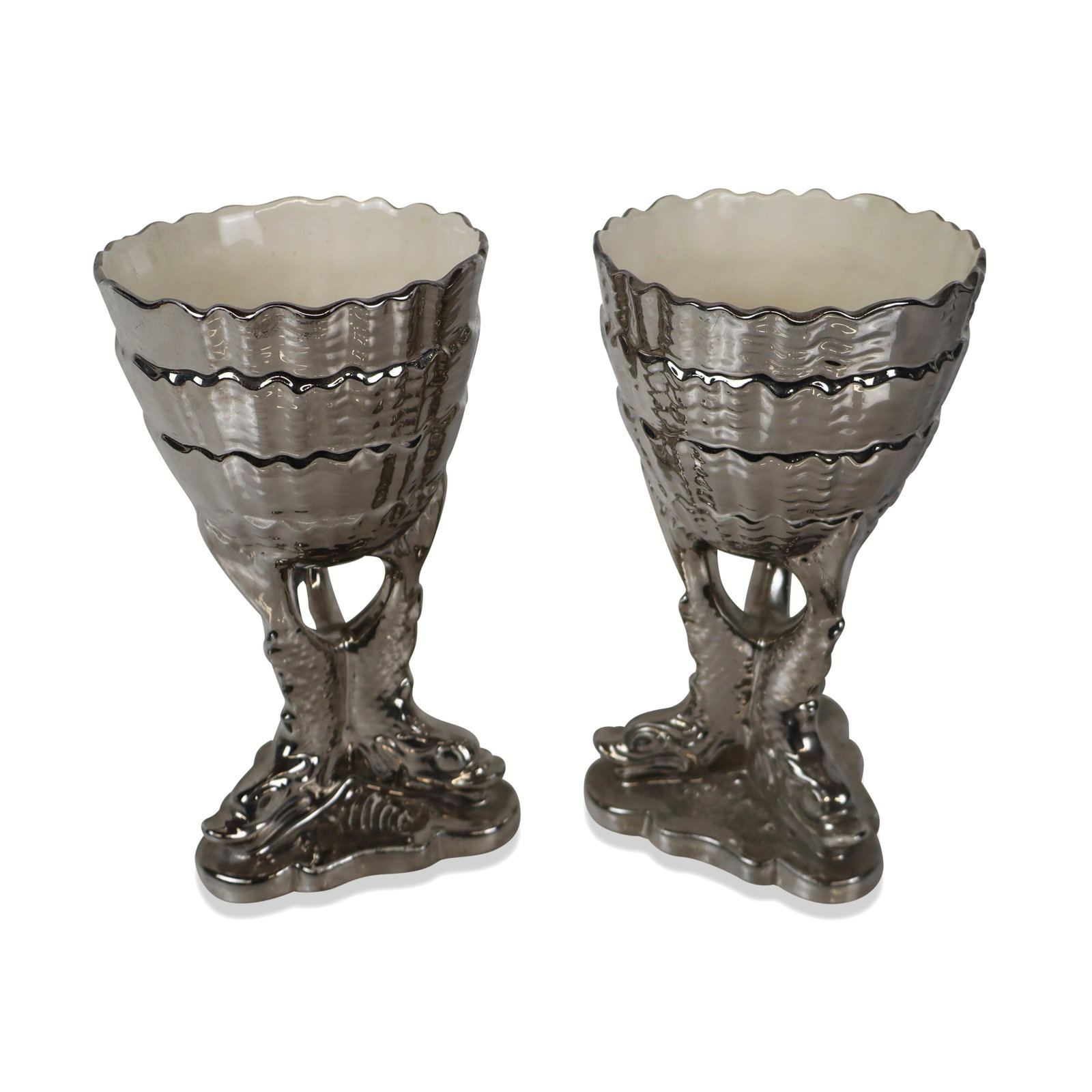 Silverine Devon Ware Pair of Porcelain Cups: S. Fielding & Co. Devon Ware Silverine pair of porcelain cups, Stokes-on-Trents, first quarter of the 20th century, designed as shell form cups raised on a tripod with dolphin feet, marks to base.