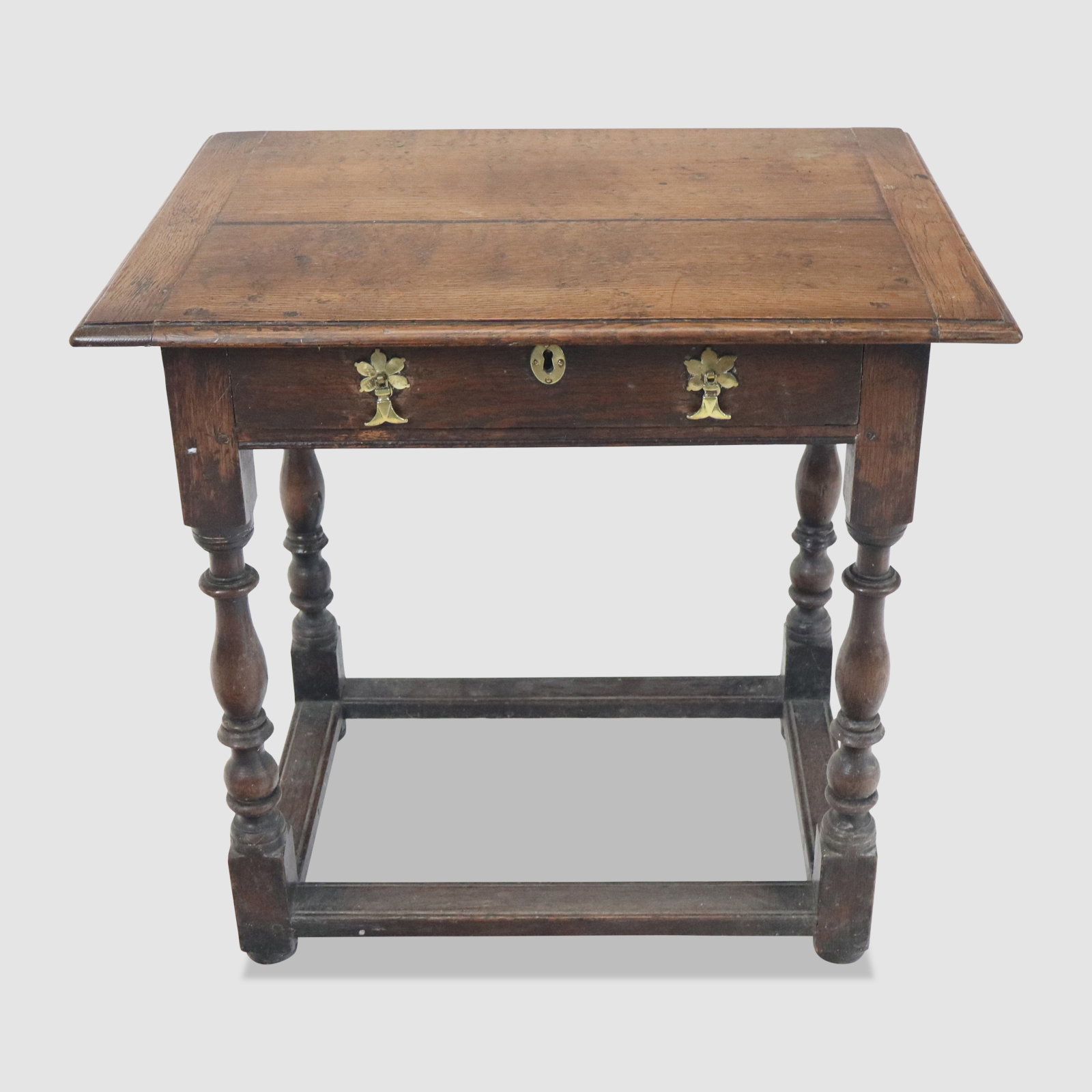 William & Mary Oak Table: William and Mary oak table, American, 18th century, with a brass mounted drawer and four turned legs with a cross-stretcher. [26" H x 26" W x 18.5" D]. Condition is good with surface wear to wood and 
