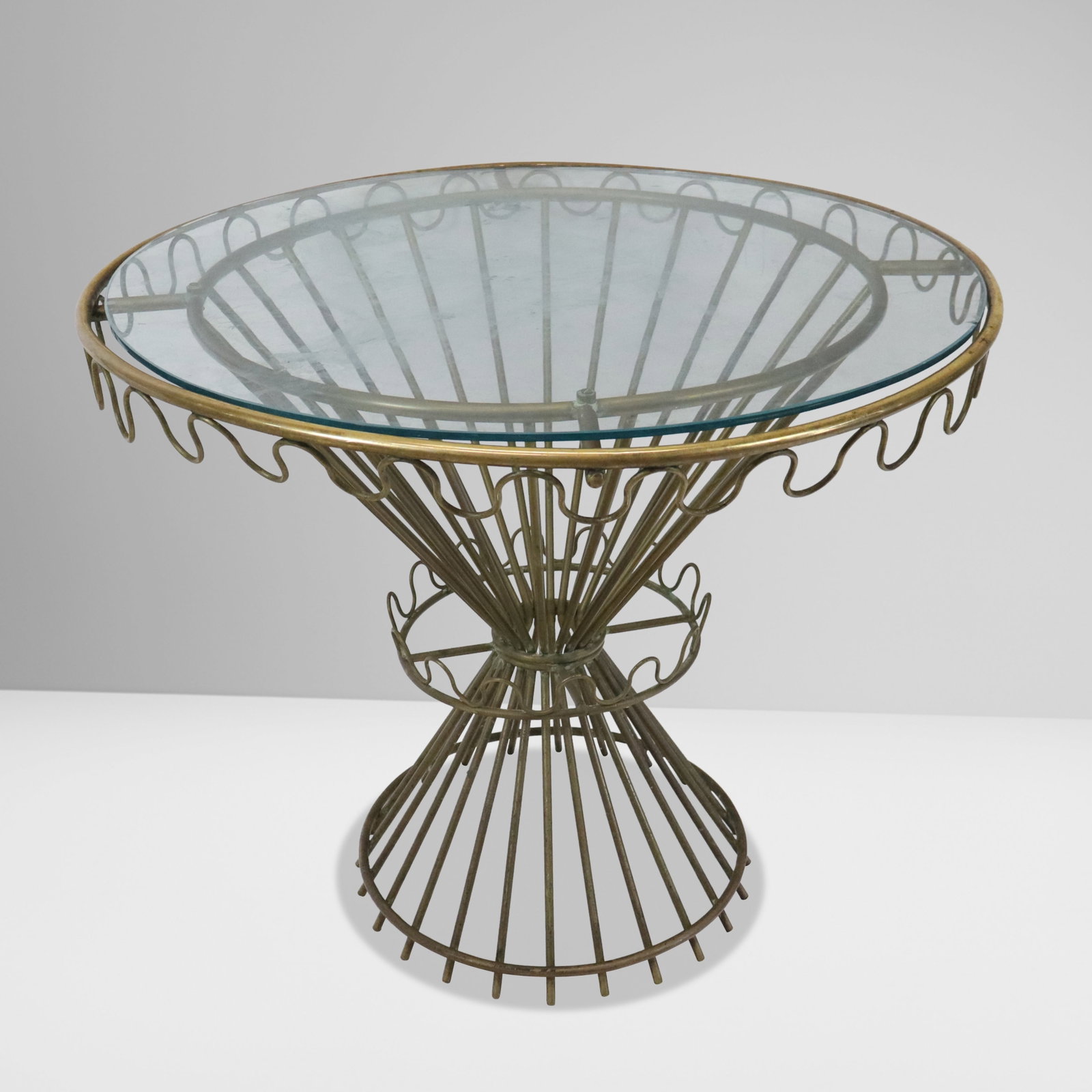 Mathieu Mategot Attrib. Cap d'Ail Table: Attributed to Mathieu Mategot Mid-Century brass Cap d'ai table, France, Mid-20th century, with an affixed glass top, unmarked. [30" H x 36" Diameter]. Condition is good with some patina and wear to br