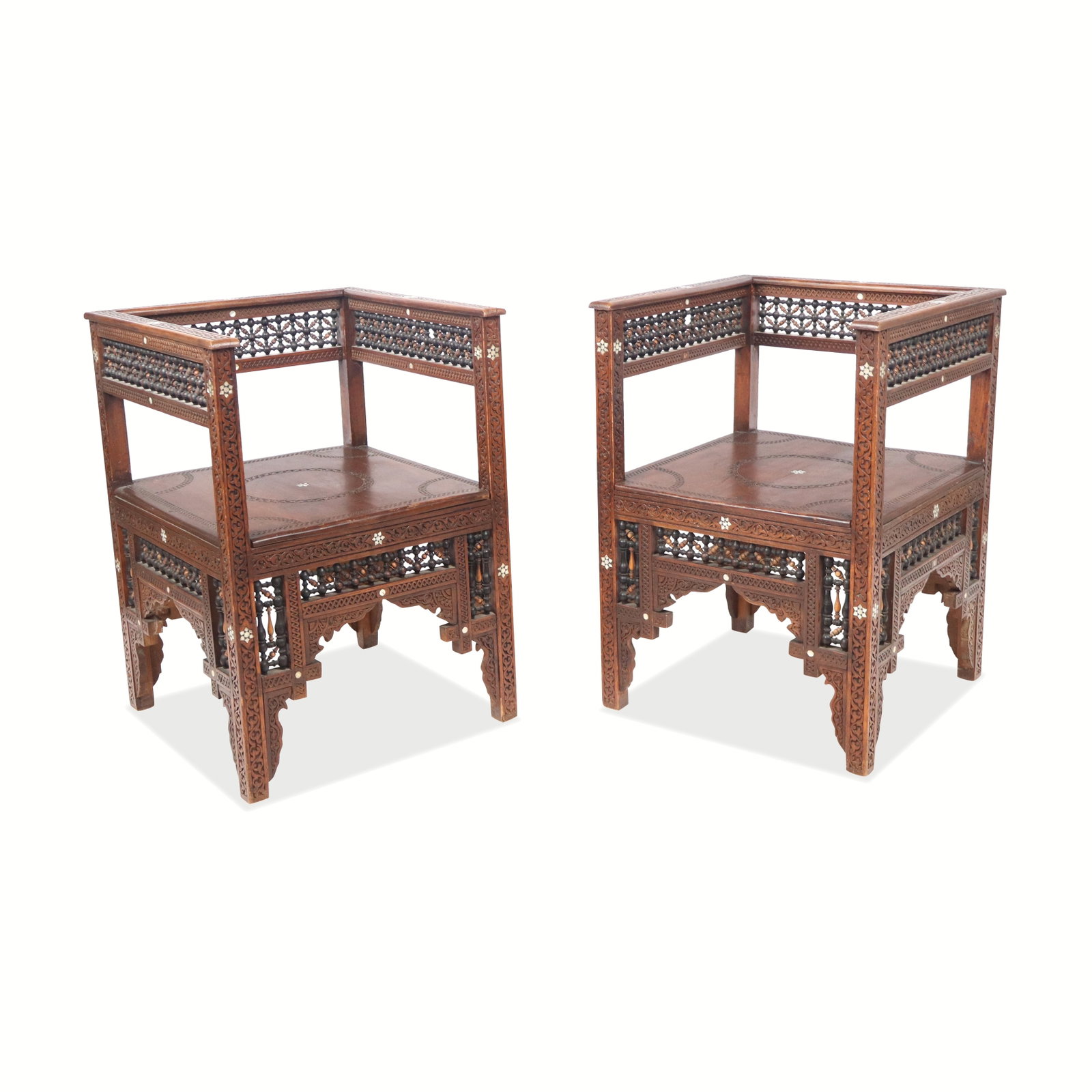 Pair of Syrian Carved and Inlaid Chairs: Pair of Syrian carved chairs, 20th century, with mother of pearl inlay and interlocking wood detail to arms and backrests. [28" H x 20" W x 20.5"; seat height: 15"]. Condition to each is good with min