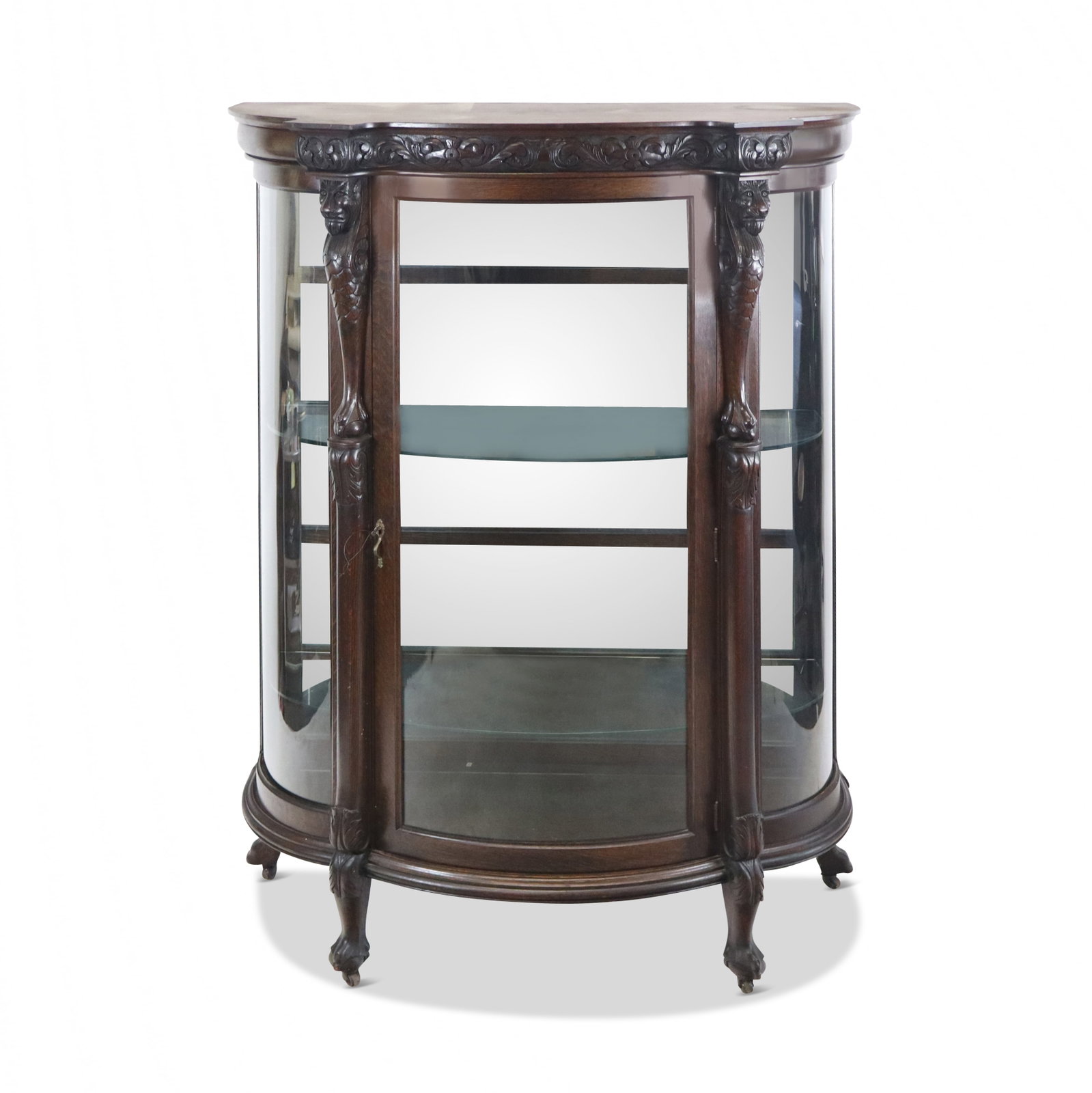 Victorian Oak Vitrine Cabinet: Victorian oak vitrine cabinet, 19th century, with carving to upper and two figural monts, on ball and claw feet, and with a mirror-backed interior. [67" H x 46.5" W x 18.5" D]. Condition is good with 