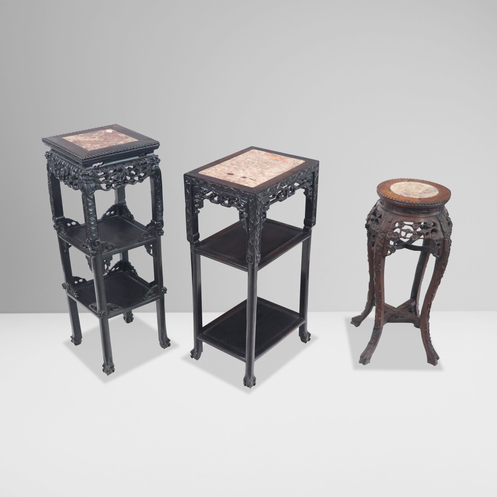 Chinese Carved Rosewood Stands, 3: Three Chinese carved rosewood stands, 19th/20th century, all with inset marble tops, and elaborate carving to lower. [Tallest: 35" H x 12" Square]. Condition is good with discoloration to marble top o