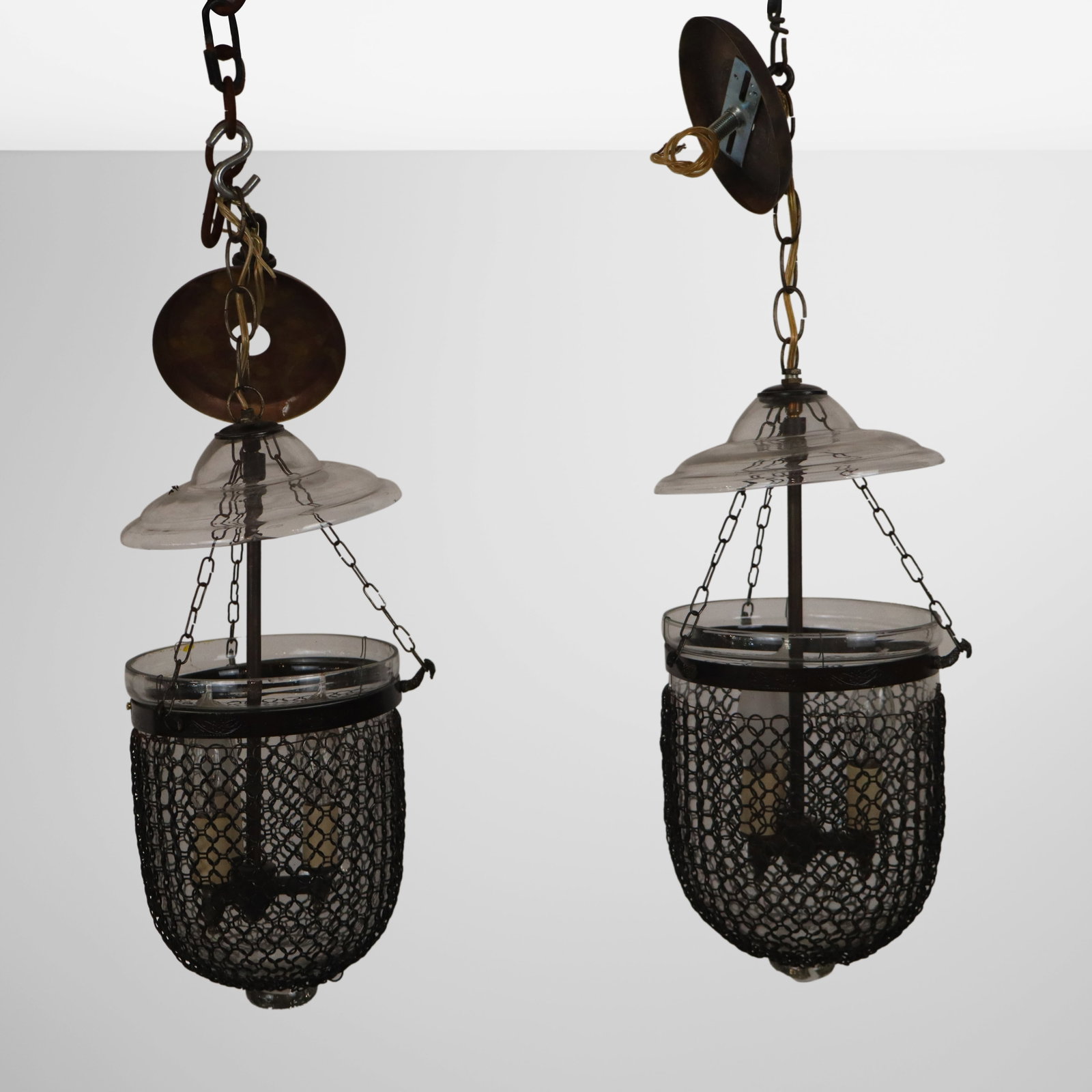 Pair of Vaughan Bell Chandeliers with Chain Detail: Pair of Vaughan bell chandeliers, 20th century, with chain detail and pressed brass trim, and hand-blown glass, unmarked. [Fixture: 17" H x 17.25" Diameter]. Condition is good with some minor chips to