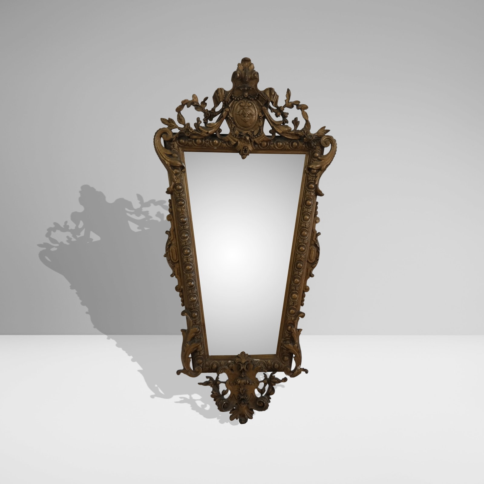 French Gilt Gesso Sculpted Mirror: French Gilt gesso sculpted mirror in angular form with a highly detailed pediment with crest and open valance over a beveled glass mirror and scrolling bellflower drop. Early 20 century. 45" H x 23" W