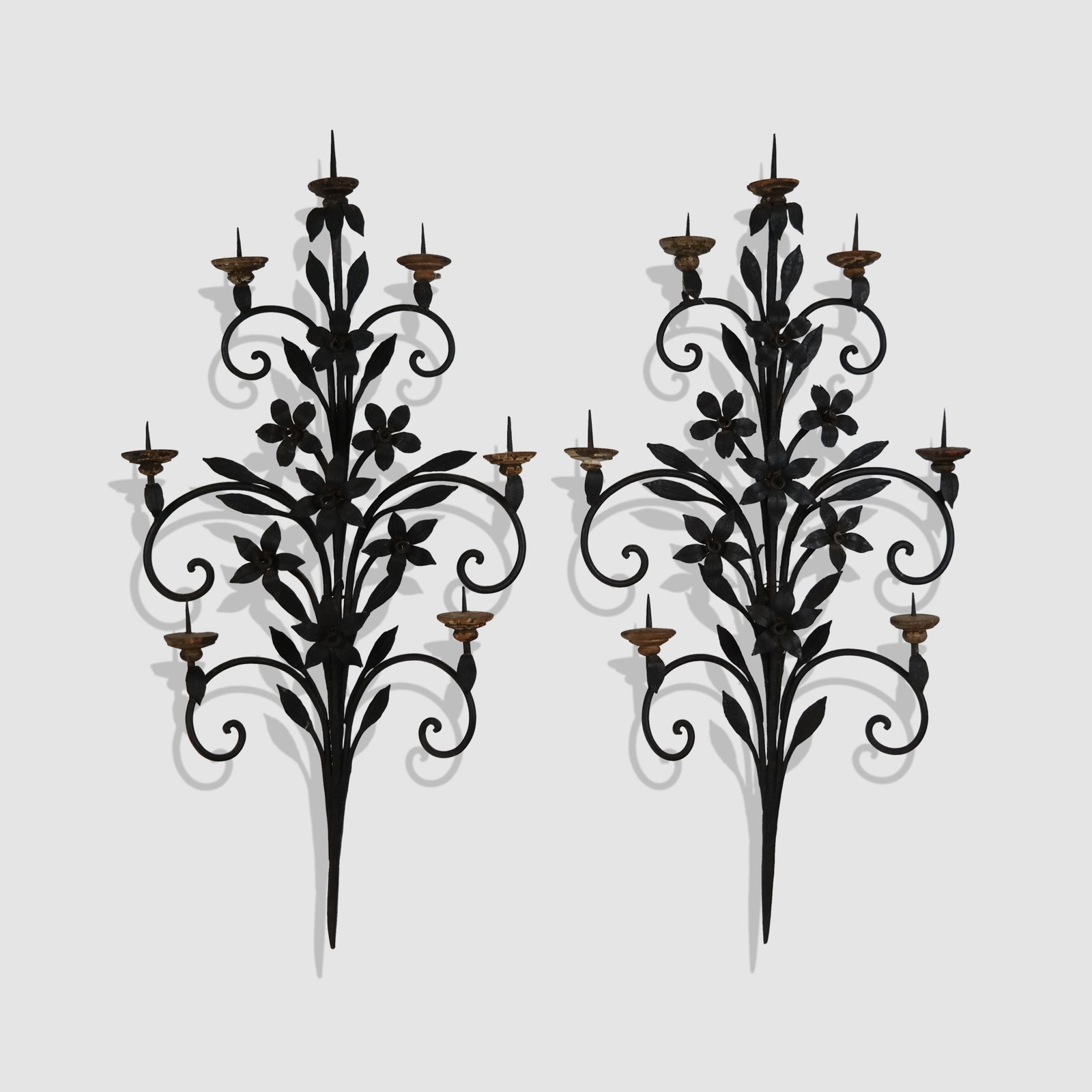 Pair of Arts & Crafts Wrought Iron Floral Sconces: Pair of Arts and Crafts wrought iron and floral decorated sconces, early 20th century, with seven pricket candle holders mounted with turned wood supports. [26.5" H x 14" W x 4.5" D]. Condition is goo
