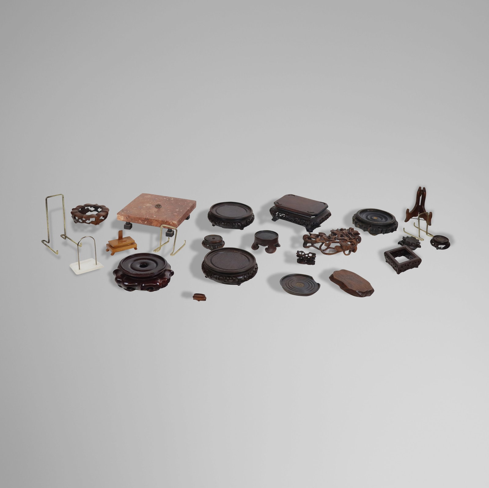 Group of Chinese Carved Wood & Other Stands, 22: Group comprising fifteen Chinese carved wood stands, a penny inset wine coaster, four plate stands, and two others. [Largest: 2.5" H x 7" W x 5.5" D]. Condition throughout is good; some with minor wea