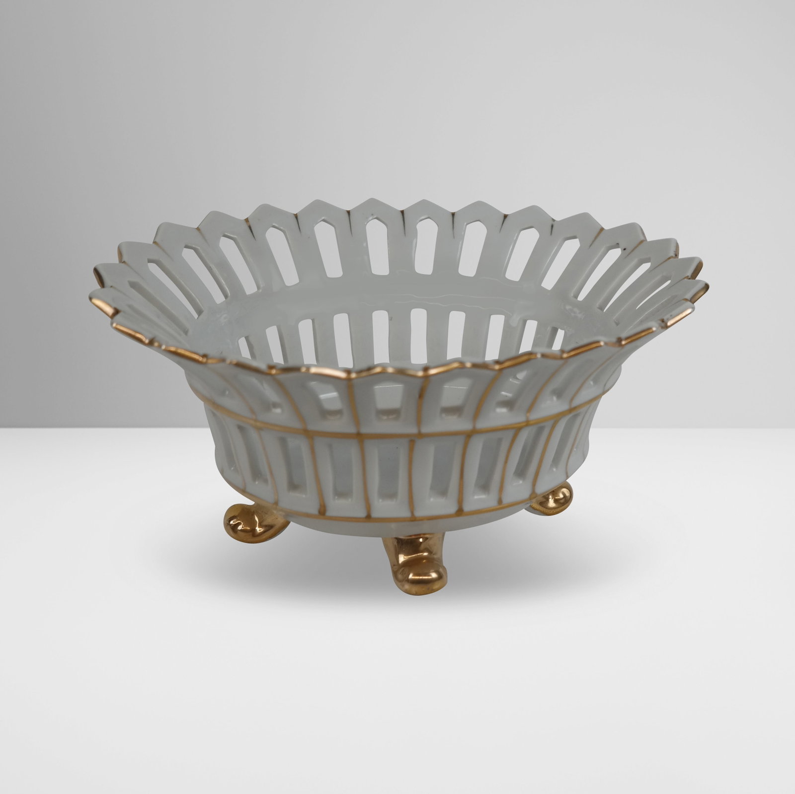 Gilt Decorated Porcelain Center Bowl: Gilt decorated porcelain center bowl, 20th century, with reticulated sides, unmarked. [4" H x 8" W x 6.25" D]. Condition is good.