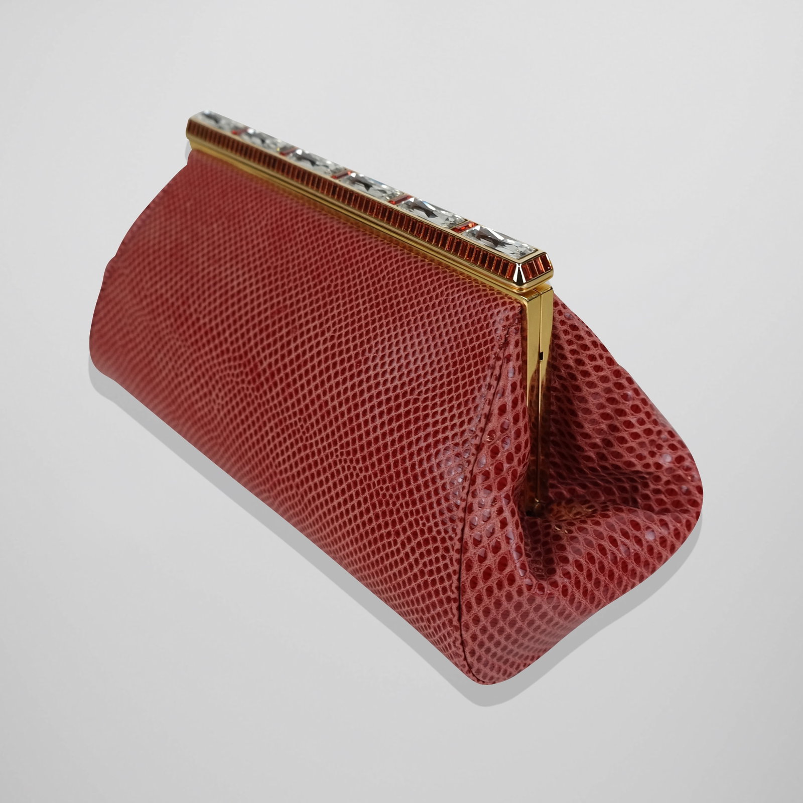 Judith Lieber Lizard Skin Clutch: Judith Lieber lizard skin clutch handbag, 21st century, with rhinestone decorated gold-tone closure, and a gold tone chain, accompanied by original matching coin purse and with dust bag. [5" H x 9.5" 