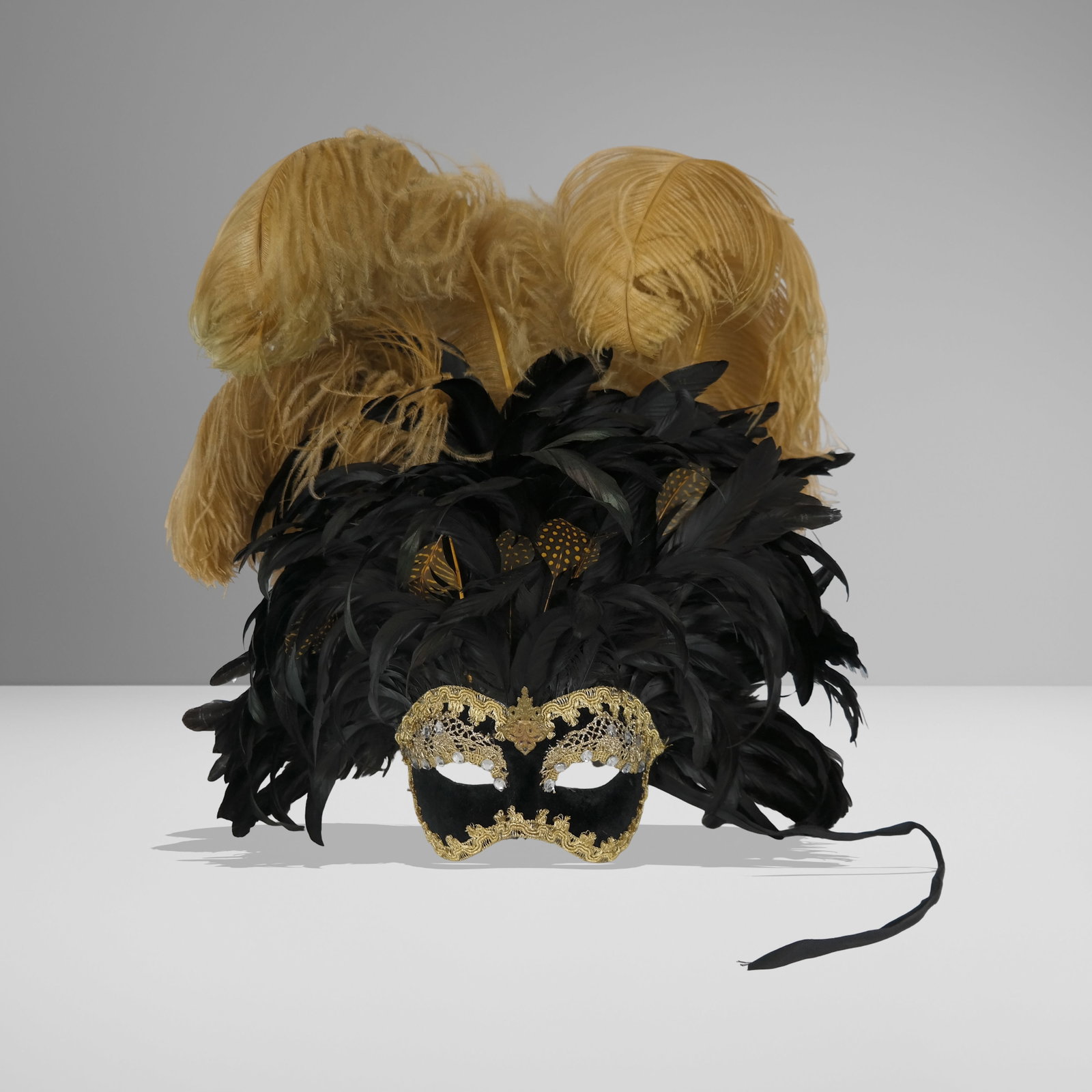 Venetian Mask with Ostrich Feathers: Venetian mask, 20th century, with gold lace and rhinestone decorated velvet to lower, and feather and ostrich feather detail to upper, unmarked. [24" H x 18" W x 7" D]. Condition is good with a loss