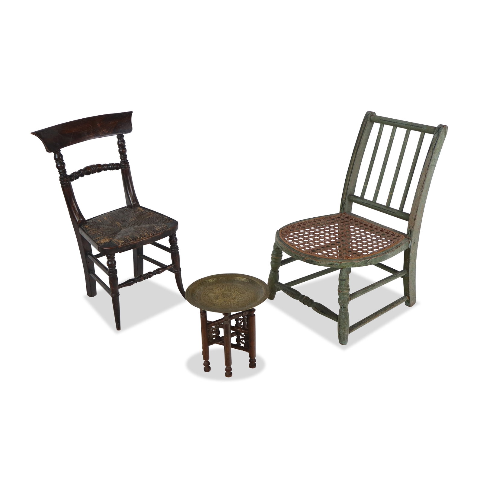 Two Diminutive Chairs and a Moroccan Table: Two diminutive chairs, 20th century, including a green painted chair with a caned seat, a carved side chair with a rush seat, and a diminutive Moroccan table with a pressed brass top and carved legs. 