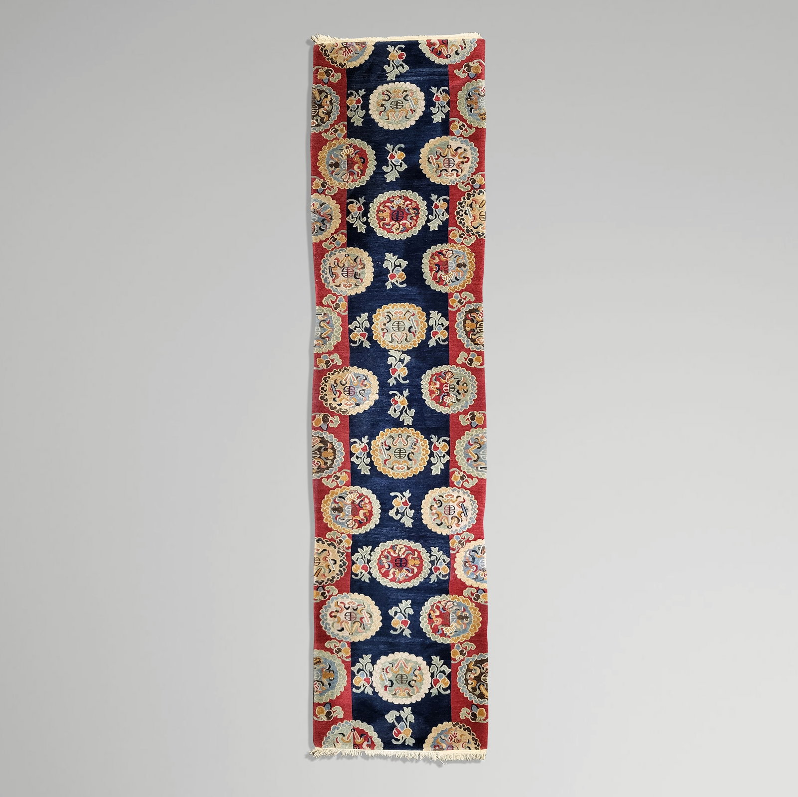 Chinese Nichols Runner: Chinese Nichols runner, the ground of deep red and blue with allover medallions [143" L x 30.5" W]. Overall condition is good.