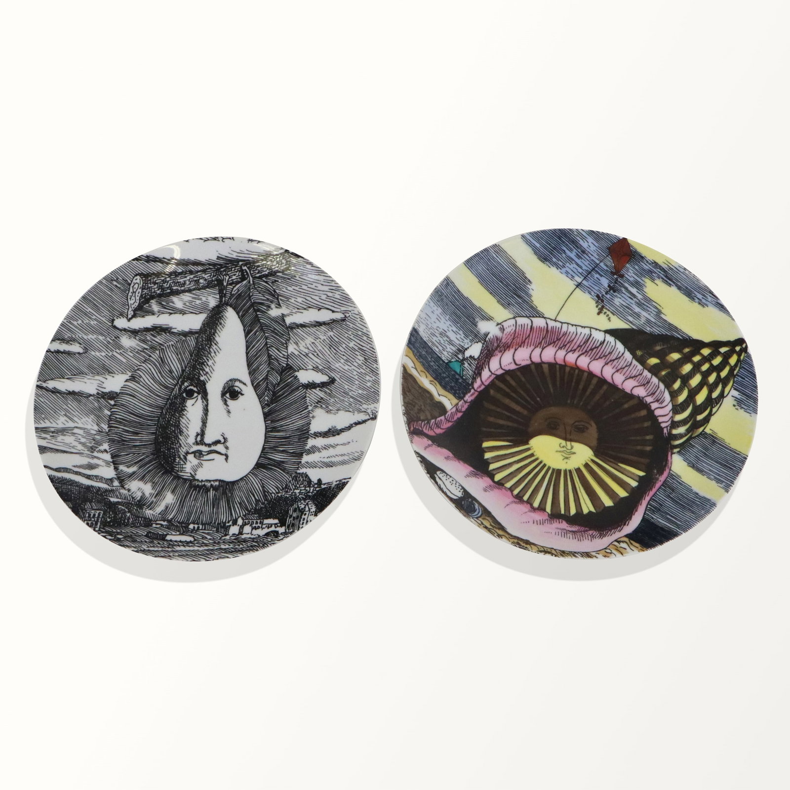 Fornasetti-Milano Porcelain Plates, 2: Two Fornasetti-Milano porcelain colored sun in seashell plate, Italian, mid 20th century, with black and white pear on branch, marked on back "12 Mesi 12 Soli".[10" Diameter]. Fine condition.