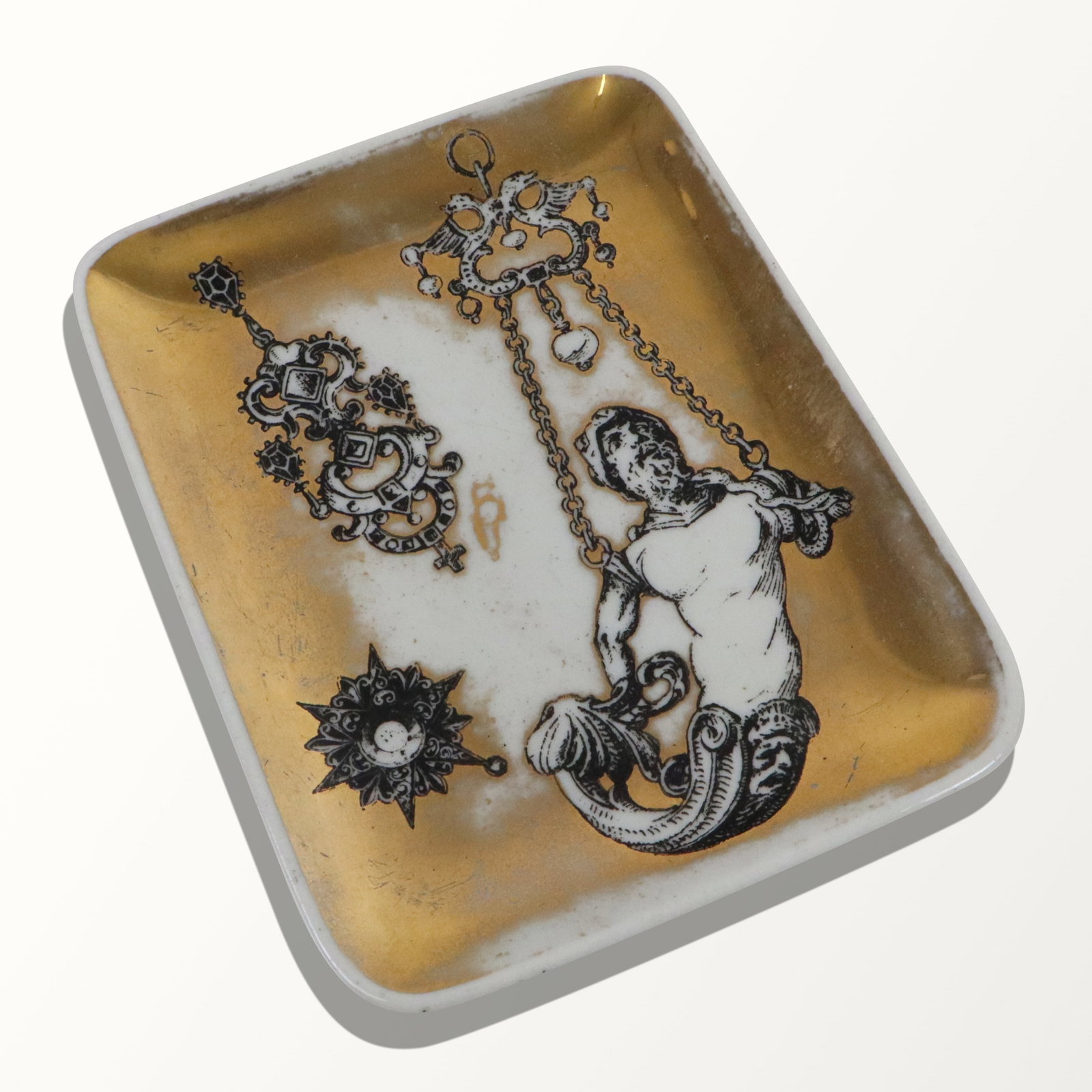 Fornasetti-Milano Porcelain Trinket Tray: Fornasetti-Milano black and gold "Vide Poche" trinket tray, Italian, mid 20th century, decorative mount designs. [4.25" L x 5.5" W]. Good condition, wear on edges.