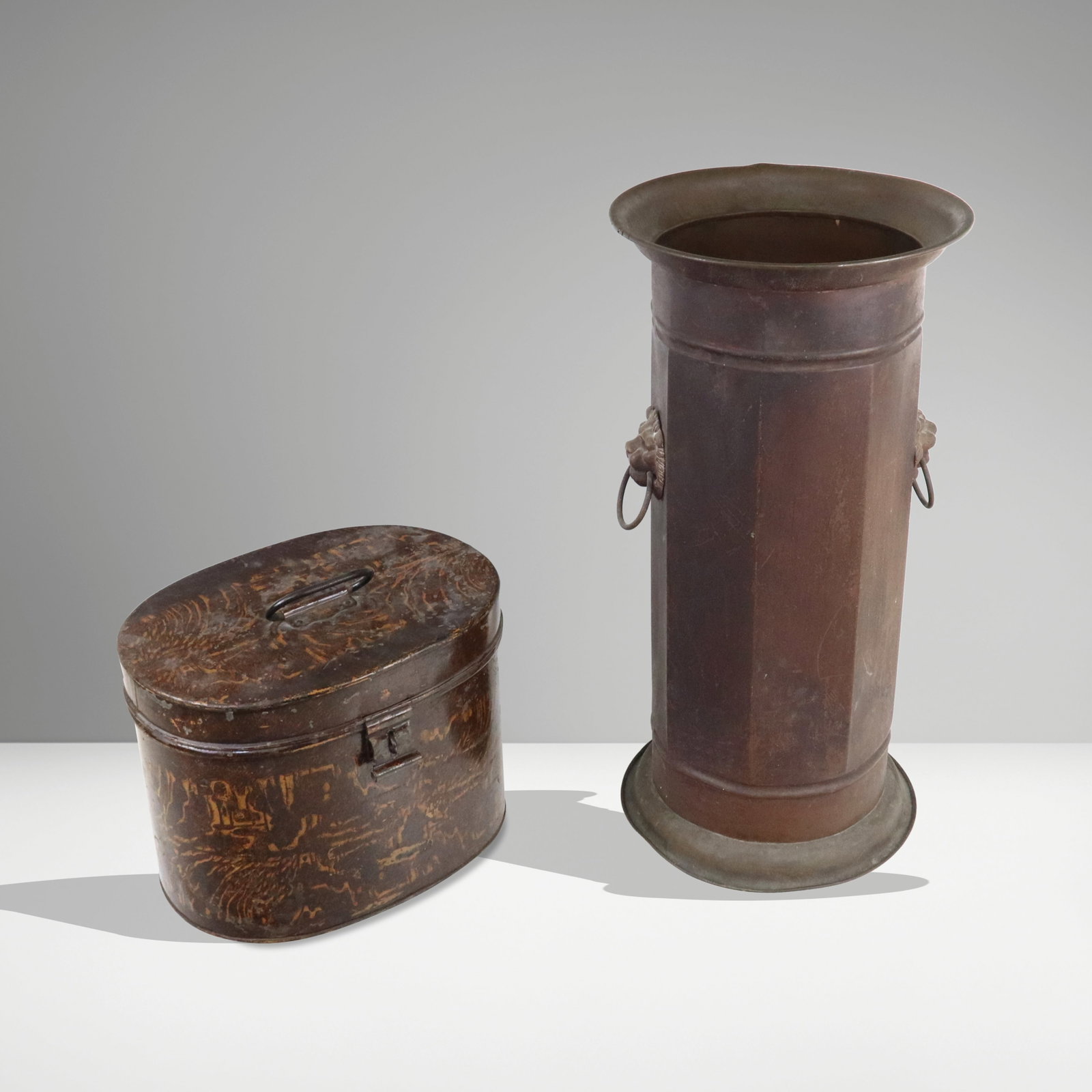 Copper Umbrella Stand & Tin Hat Box: Two metal articles, American, early 20th century, comprising a copper umbrella stand with lion head ring handles [22" H x 11" Diameter]; and a grain painted oval tin top hat box, with top handle, and