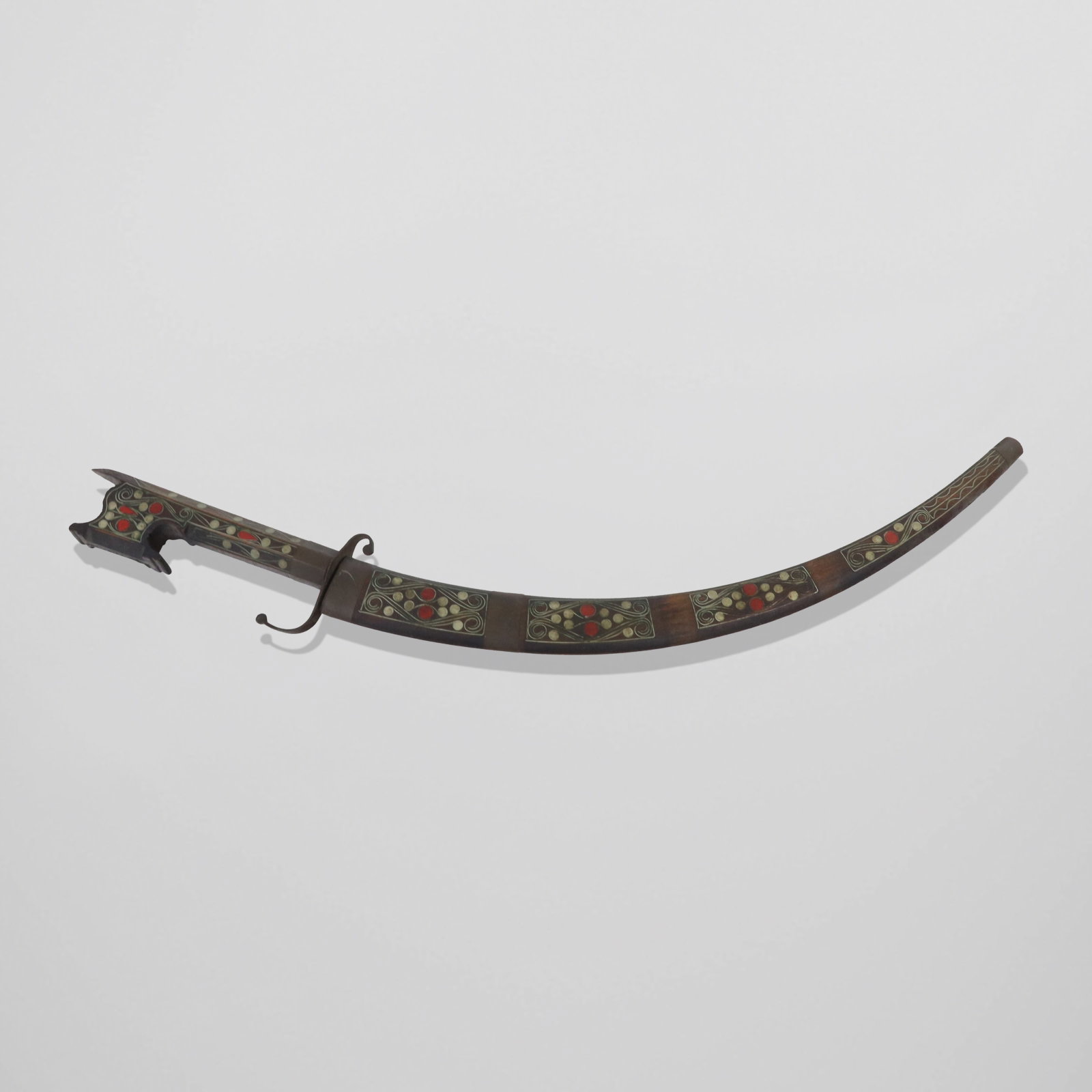 Moroccan Sabre in Wood Sheath: Moroccan saber in wood sheath, silvered line inlays and red composite mounts, carved and shaped handle, slight engraving on blade. [24" long]. Good condition, blade has rust.