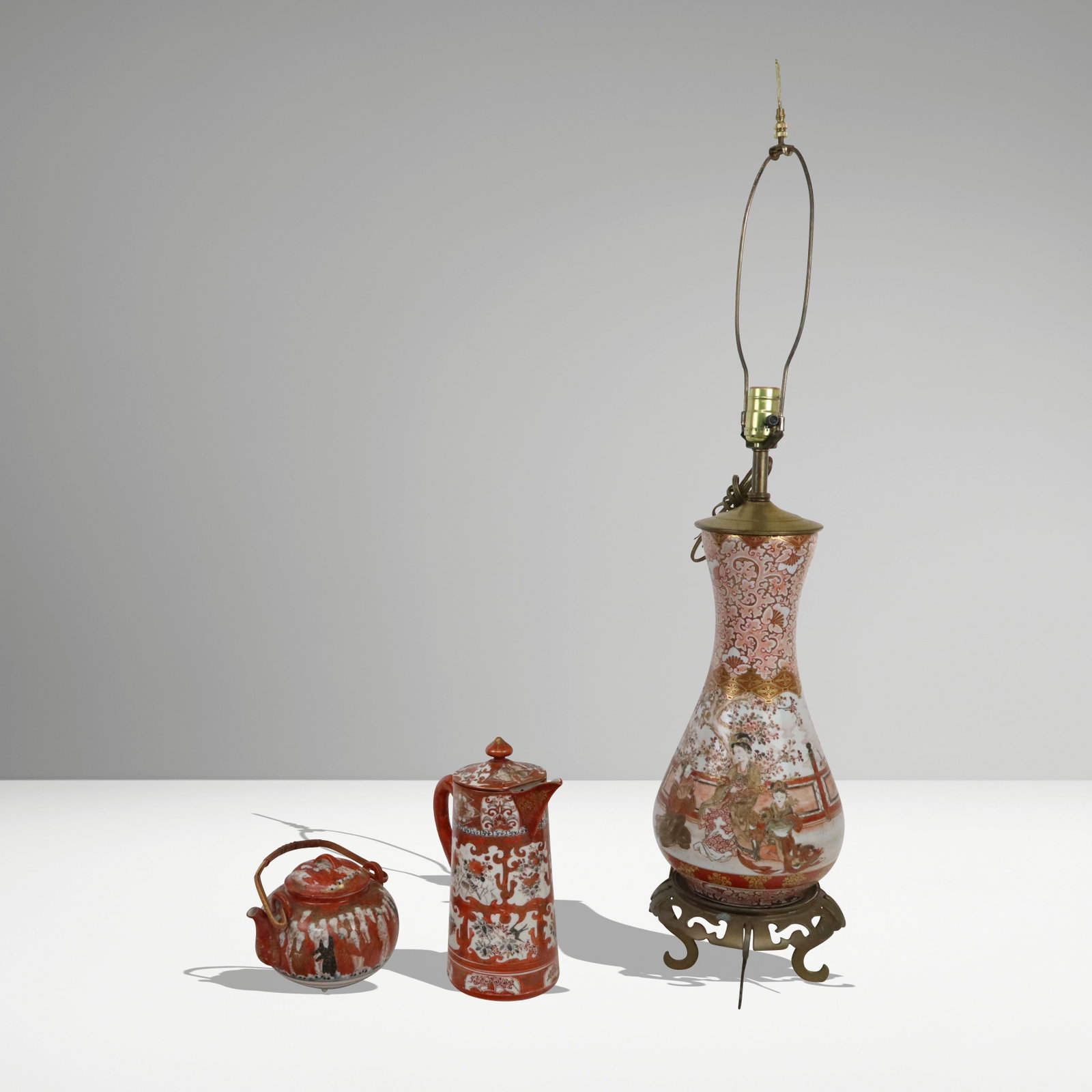 Three Japanese Kutani Articles: Three Japanese Kutani articles; tapered vase lamp with figural designs and gilt metal mounts [vase 15" H; lamp 38" H], covered pitcher with angular spout [10.5" H], and a squat low teapot with wise me