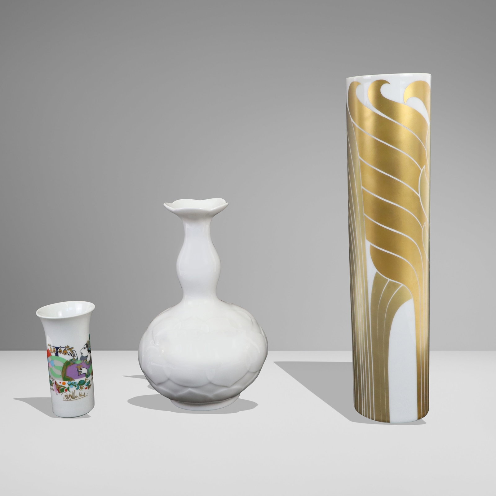 German Porcelain Vases. Three: German porcelain vases, Three; Tall Rosenthal with gilt design, short Rosenthal with color design, and floral shaped white by Meissen. [Tallest (gilt) 12"]. Good condition.