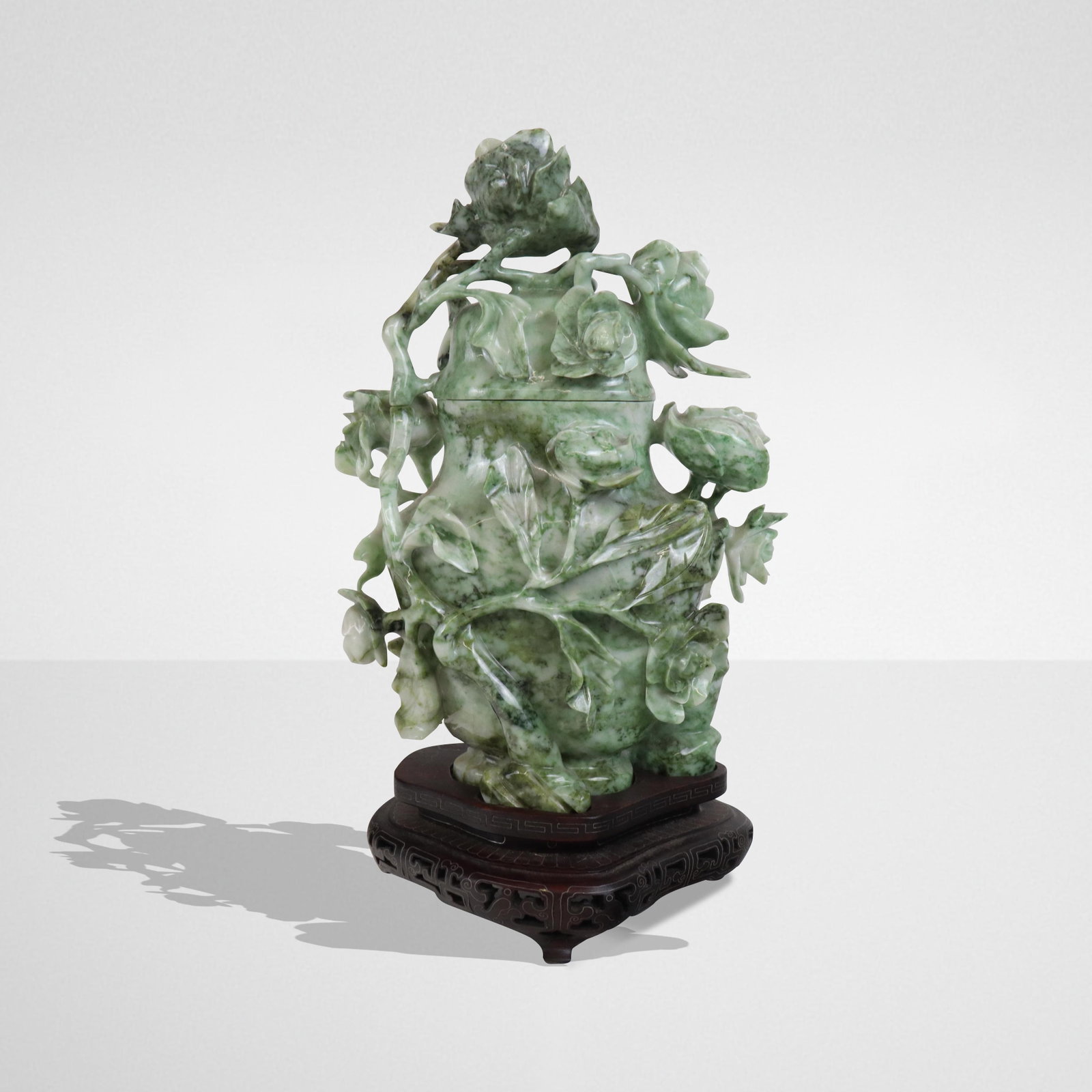 Carved Stone Covered Vase on Stand: Carved stone covered vase on stand, jade like stone in green and white with all over floral vine design, silvered line inlaid fitted stand. Mid to late 20th century. [11" H x 7" W x 4" D total]. Very 