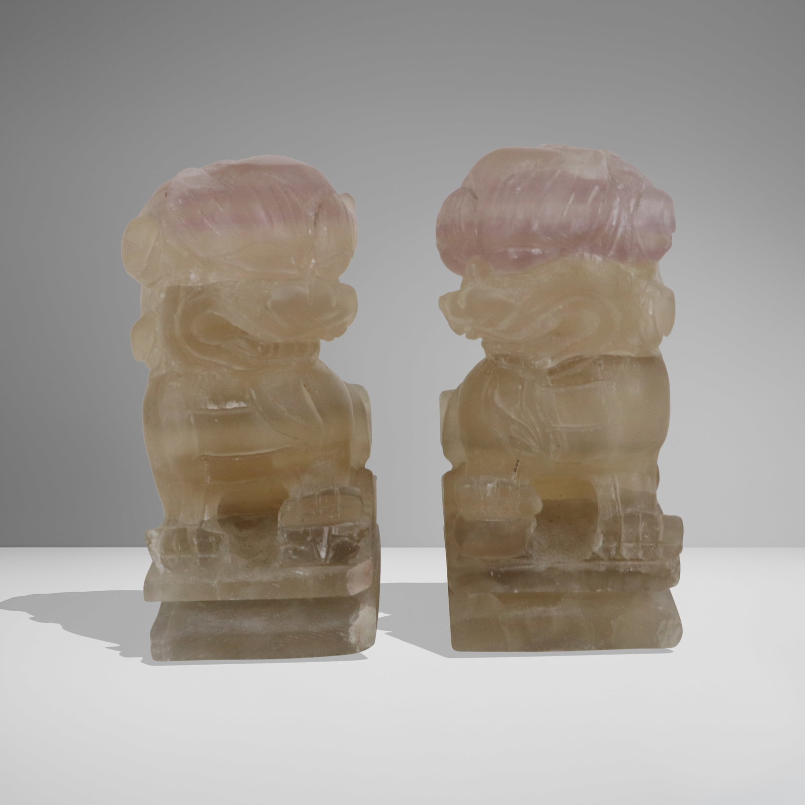Pair Small Rose Quartz Foo Lions: Pair small rose quartz foo lions, as entry guardians, mid 20th century Chinese, left facing and right facing, one with ball underfoot. [4" H]. Each with natural cracking.