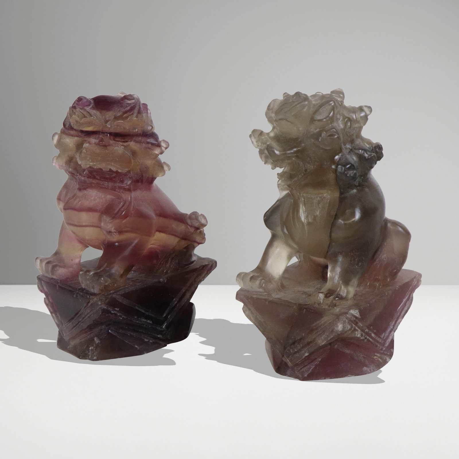 Pair Quartz Carved Foo Lions: Pair quartz carved foo lions, Chinese mid 20th century, amethyst and smokey quartz, left and right facing, [4" H]. Good condition, minor chipping.