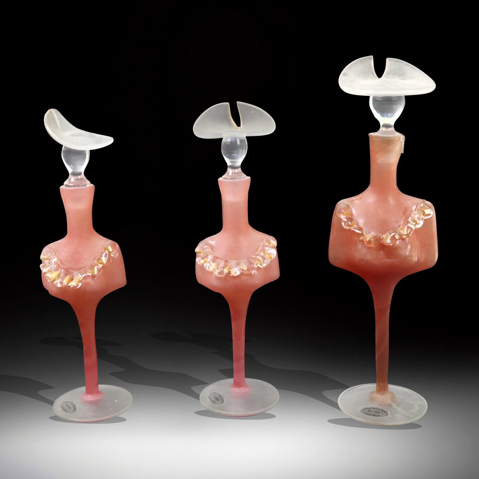 Set of Three Elena Pink Art Glass Figural Perfumer: Three Elena pink art glass figural perfumers, pink with gilt trim neckline and gilt trim on cut hat. German, 20th century. [Tallest 11.5" H]. Tallest has break on neck.