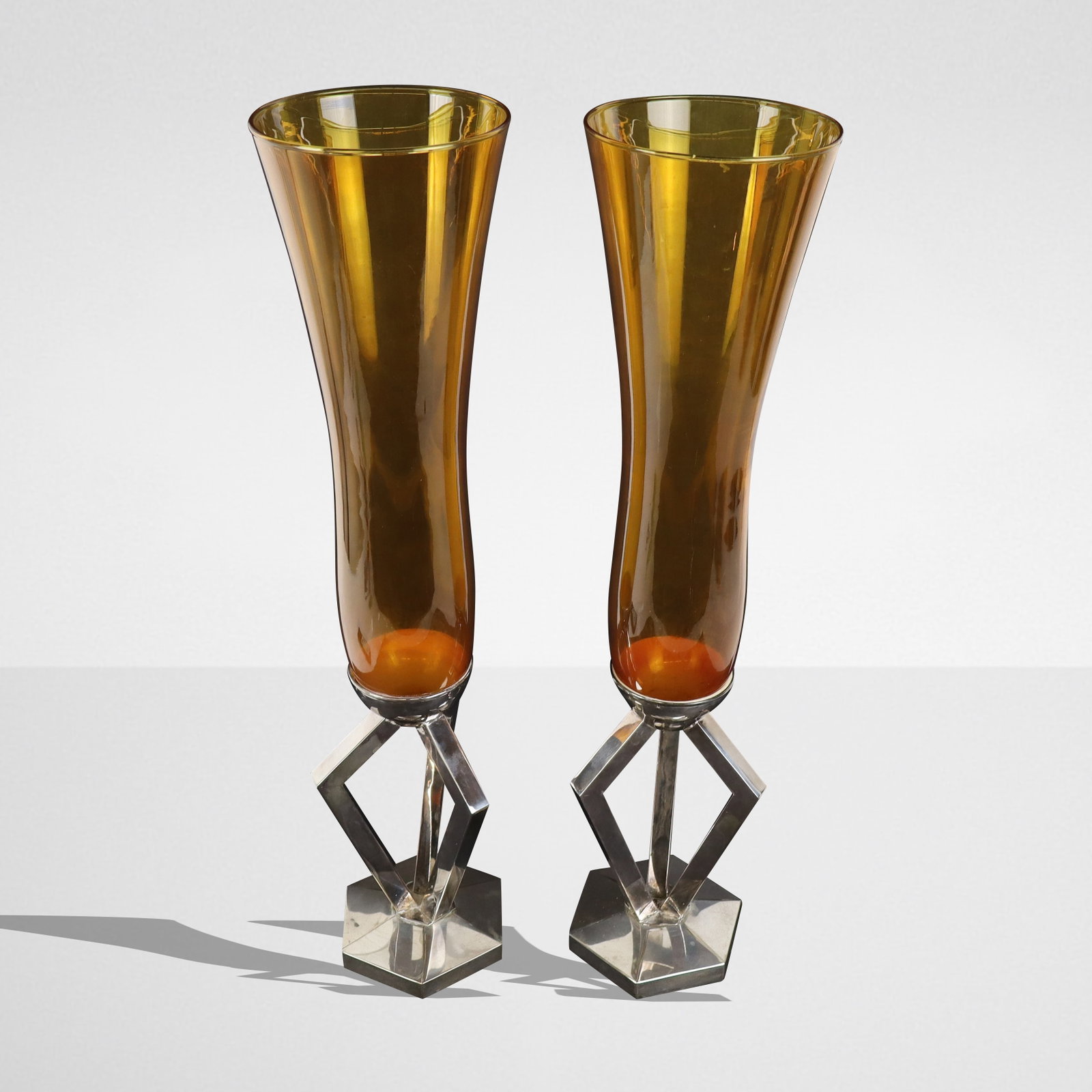 Pair of French Silver & Amber Glass Trumpet Vases: Pair of French silver and amber glass stylized trumpet vases, the slightly flared amber glass vessel resting on a weighted sterling silver tripod foot with angular supports and hexagonal base, with