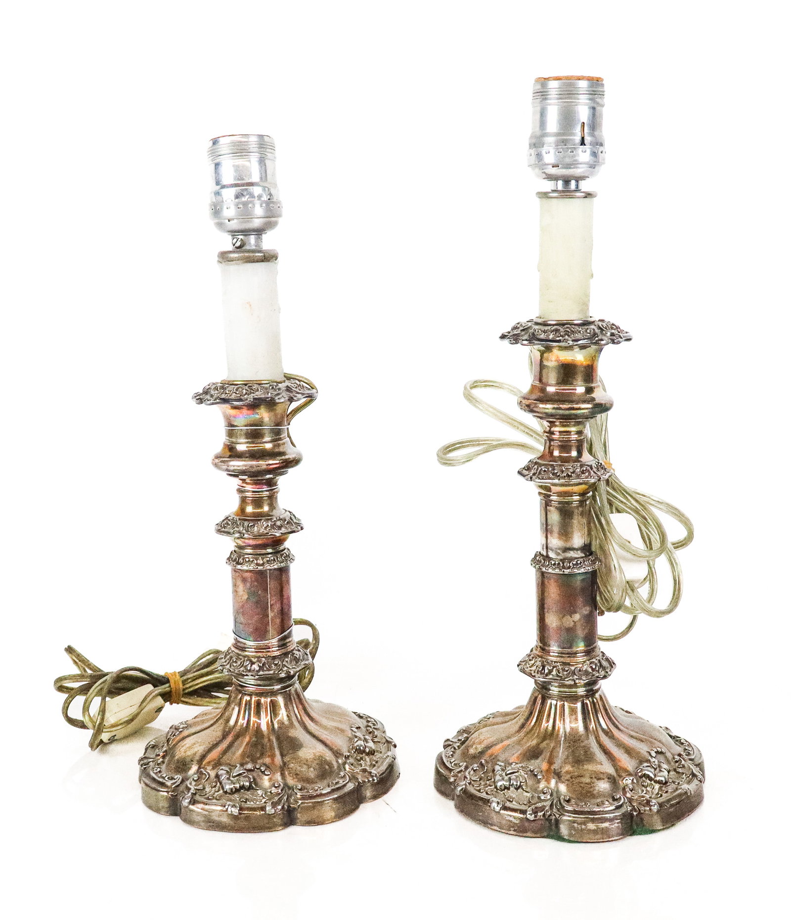 Pair of Silver Plate Candlesticks as Lamps: Pair of silver plate candlesticks, 19th century, later mounted as lamps, with repousse decoration throughout and faux wax candle cover stems. [To top of socket: 14" H x 5.25" Diameter]. Condition to e