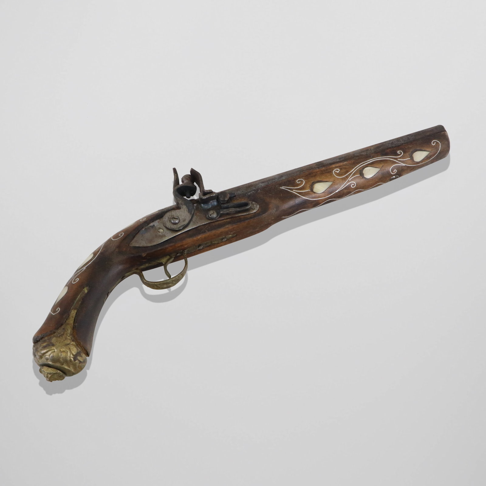 Mother of Pearl Inlaid Reproduction Flintlock: Mother of pearl inlaid reproduction flintlock pistol, with silver tone line inlays, brass mountings, in Turkish manners. [16" long]. Fair condition, loose and sharp mounts, aged wood.